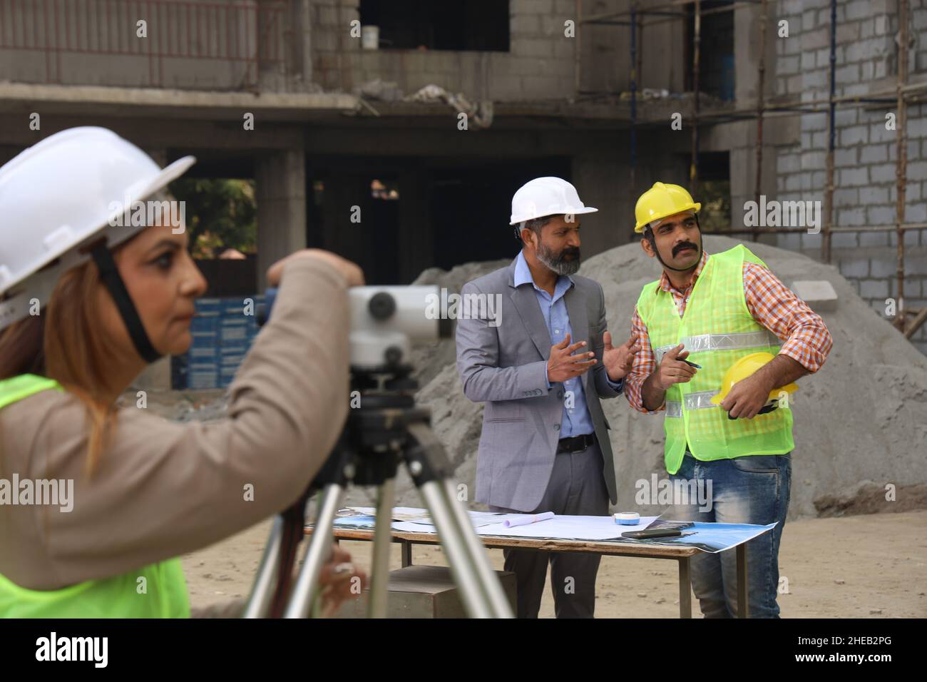 Operai di costruzione indiani. Ingegneri edili che lavorano su un cantiere edile indossando un elmetto. Analisi di BluePrint. Foto Stock