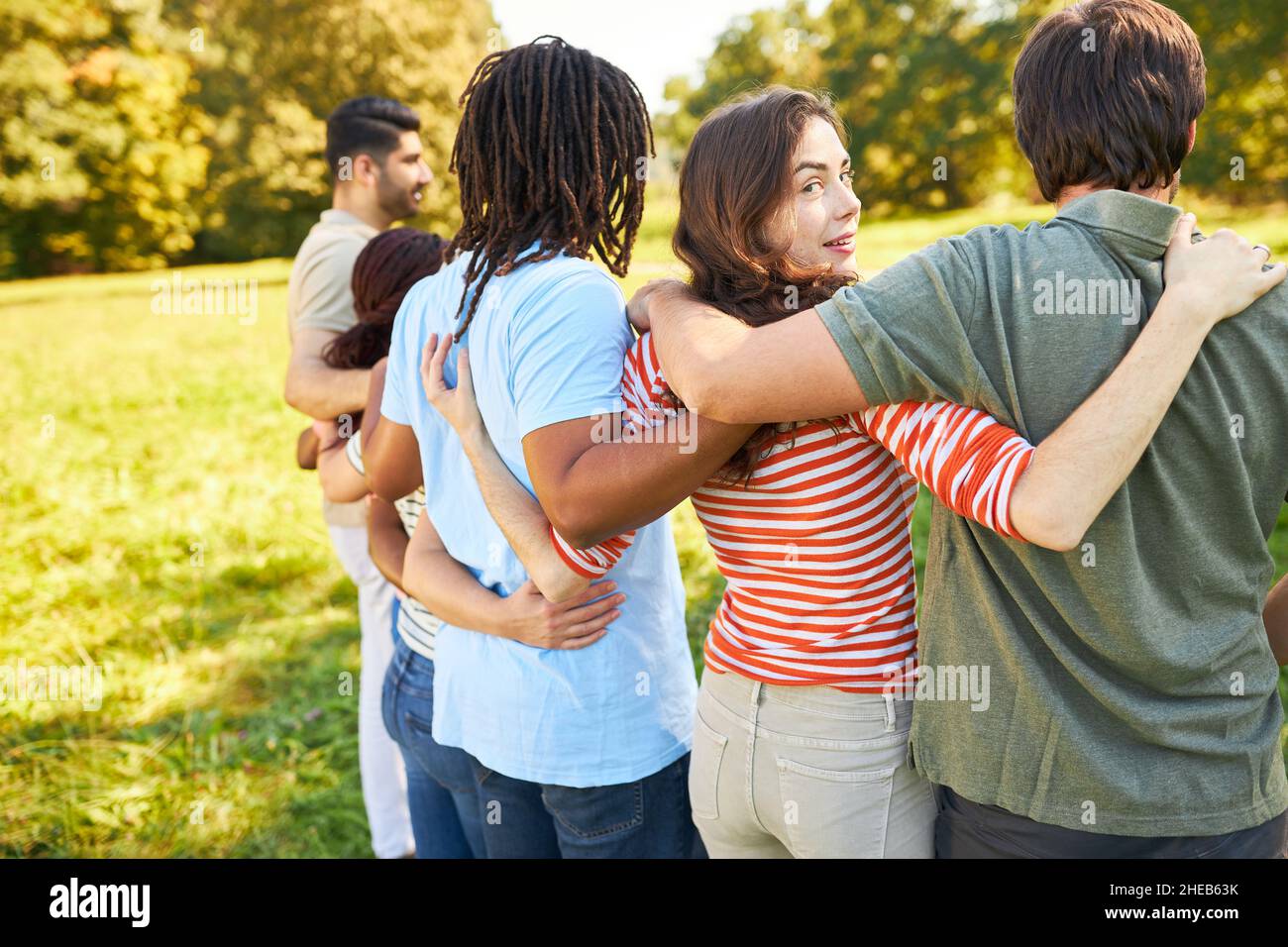 Gruppo di giovani abbracciano come amici o studenti in natura in estate Foto Stock