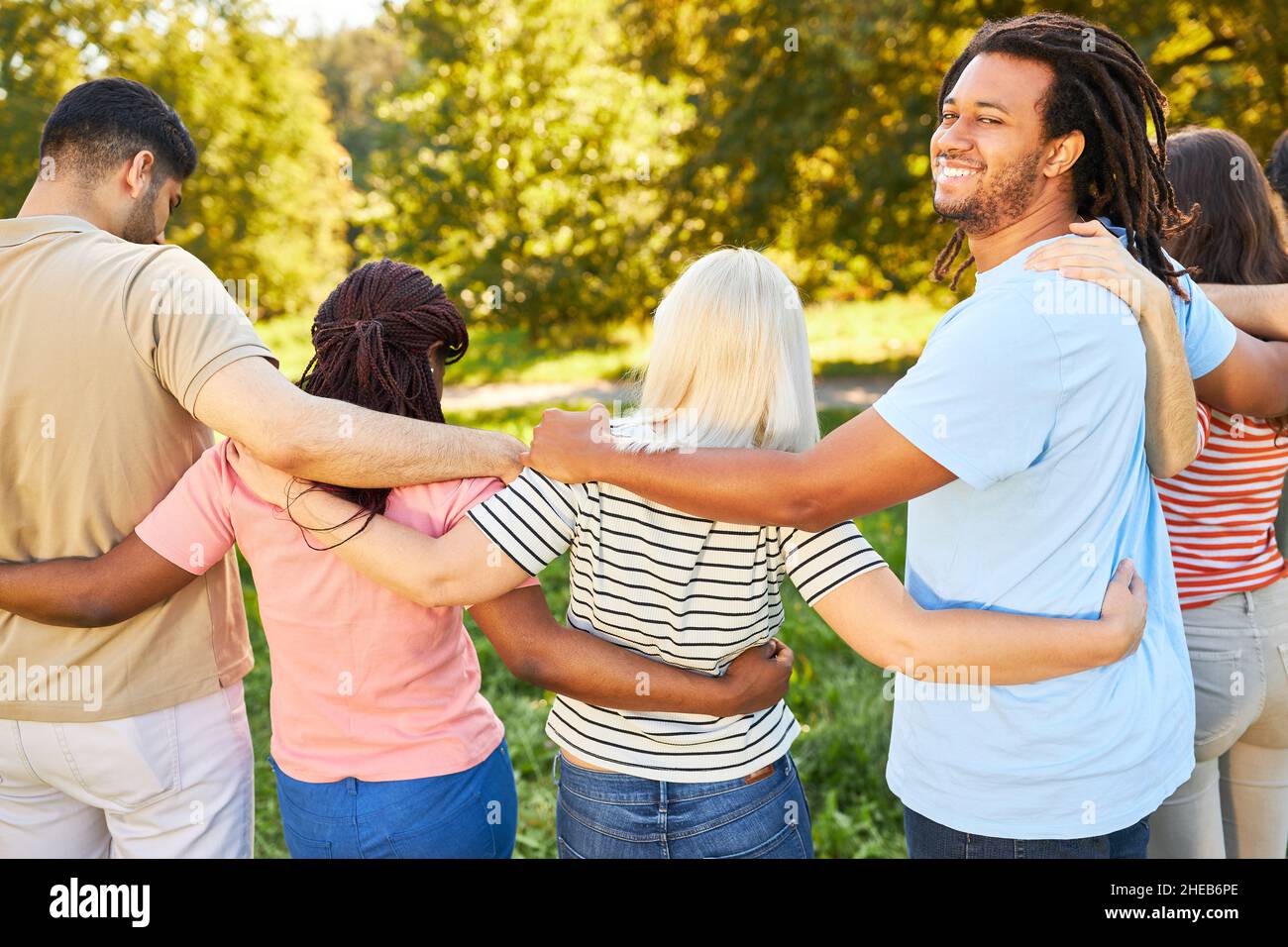 I giovani come gruppo diverso si abbracciano a vicenda in un'escursione estiva nella natura Foto Stock