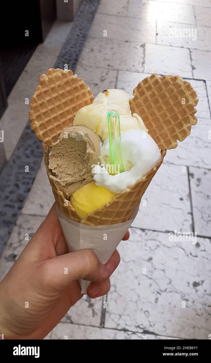 Morsi il cono gelato in mano. In forma di palline multicolore con orecchie Foto Stock