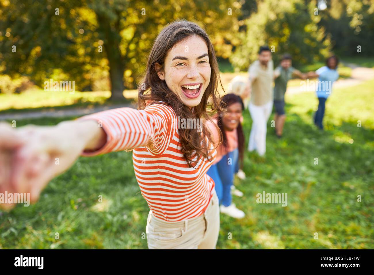 La giovane donna che ride si alza di pari passo con gli amici in un gioco di team building Foto Stock