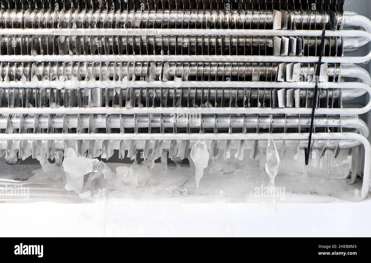 Il tappo di drenaggio di un congelatore senza antigelo è bloccato con ghiaccio, dovendo rimuovere il rivestimento protettivo per sbloccare fondendo con un asciugacapelli. Foto Stock
