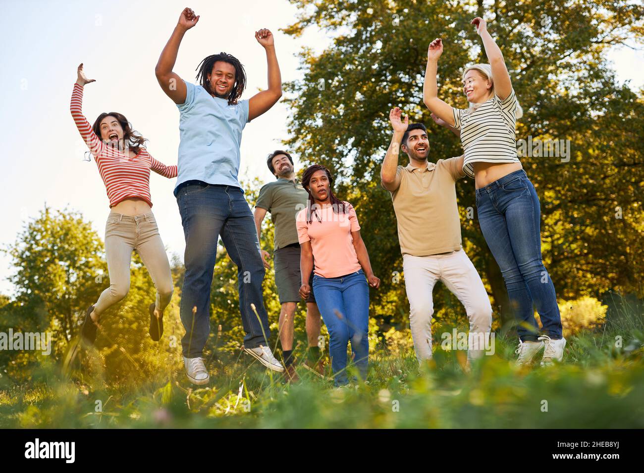 Gruppo di persone multiculturali come amici che saltano e si acclamano insieme nella natura Foto Stock