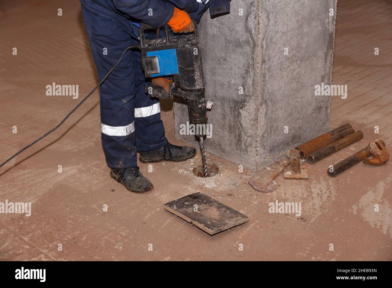 Lavoratore con martello. Perforazione e riparazione di superfici in calcestruzzo da parte di un operatore maschio con martello pneumatico. Lavoratore professionale. Foto Stock