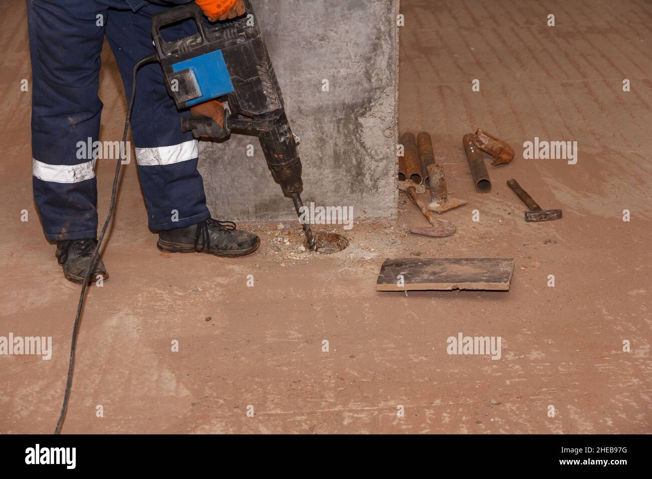 Lavoratore con martello. Perforazione e riparazione di superfici in calcestruzzo da parte di un operatore maschio con martello pneumatico. Lavoratore professionale. Foto Stock