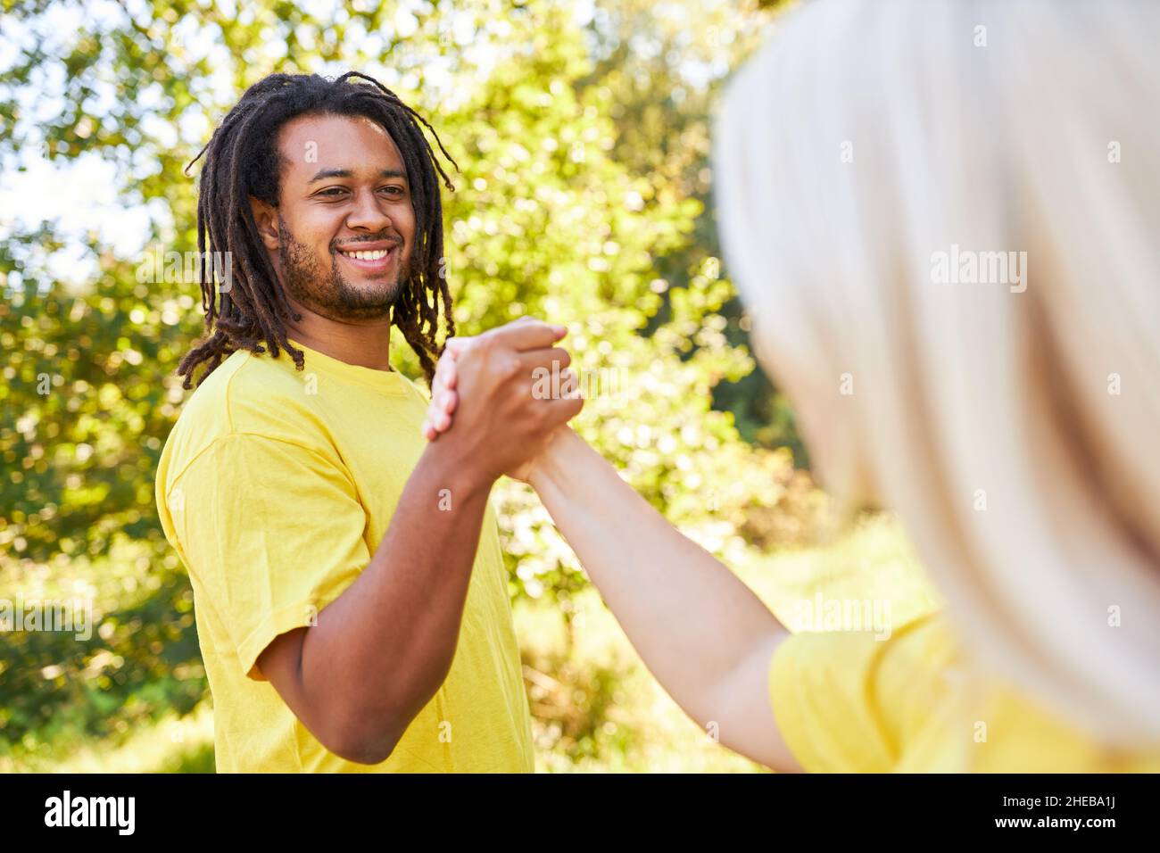 Due giovani che fanno il handshake come saluto o come esercizio di team building in estate Foto Stock
