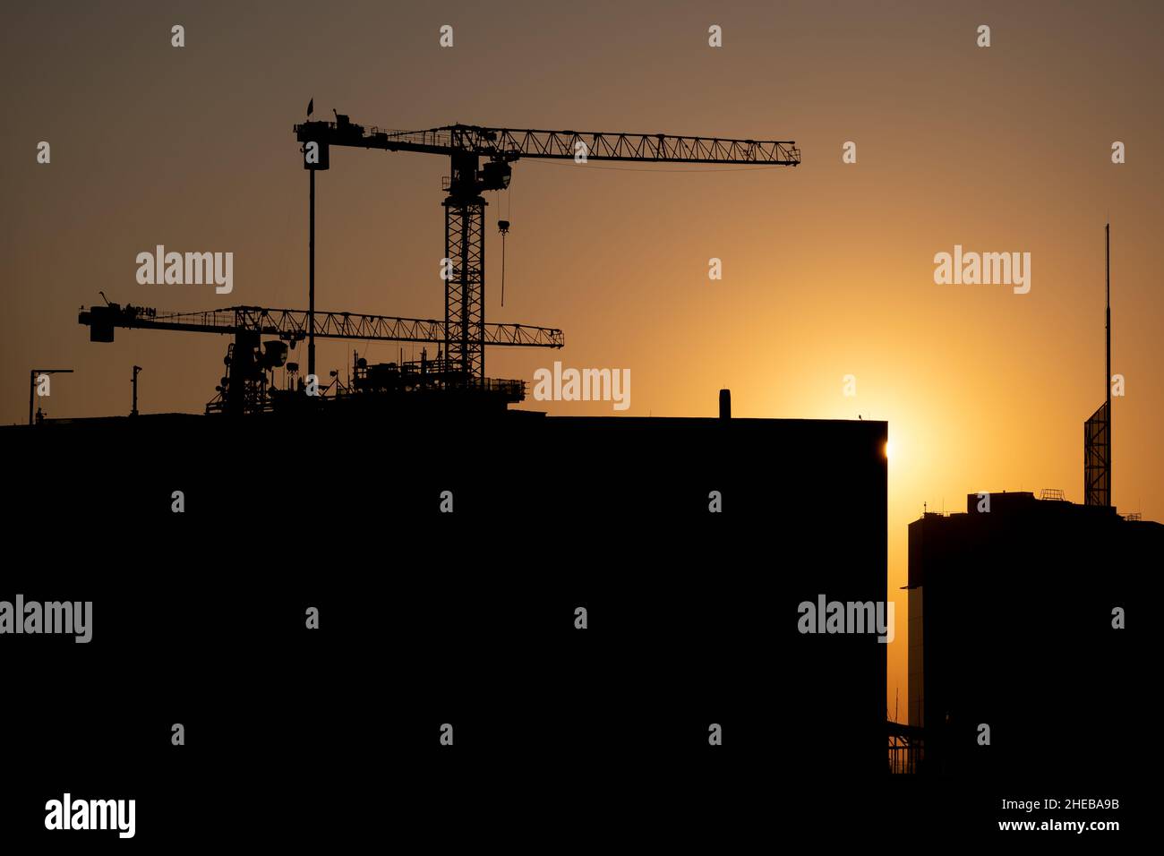 Cantiere al tramonto, grattacielo in apice con sole tramontato sul bordo di un edificio. Foto Stock