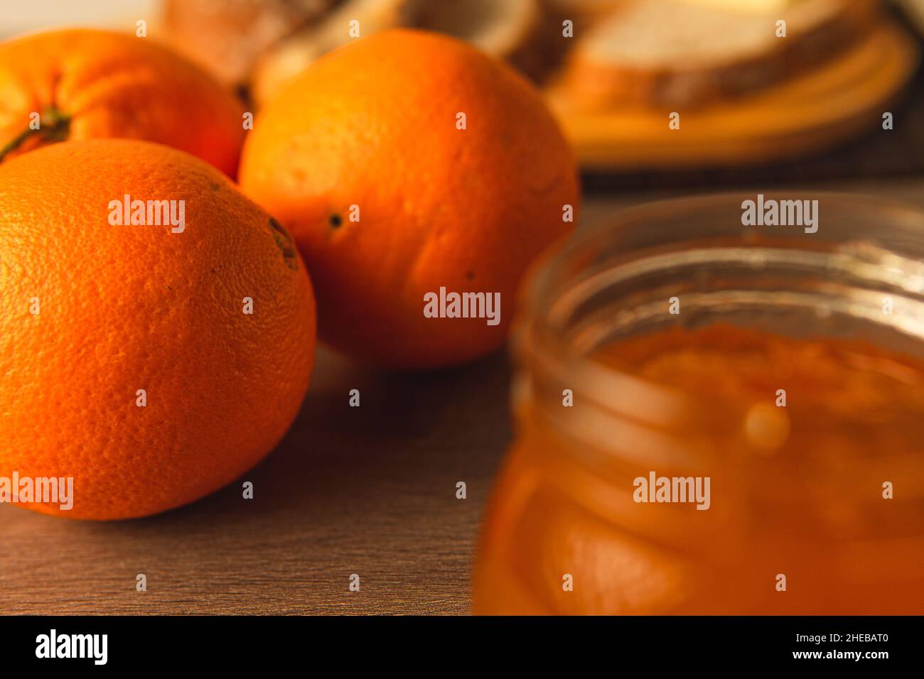 Arance dolci naturali per fare la marmellata in un contenitore con pane rustico sullo sfondo per una ricca colazione Foto Stock