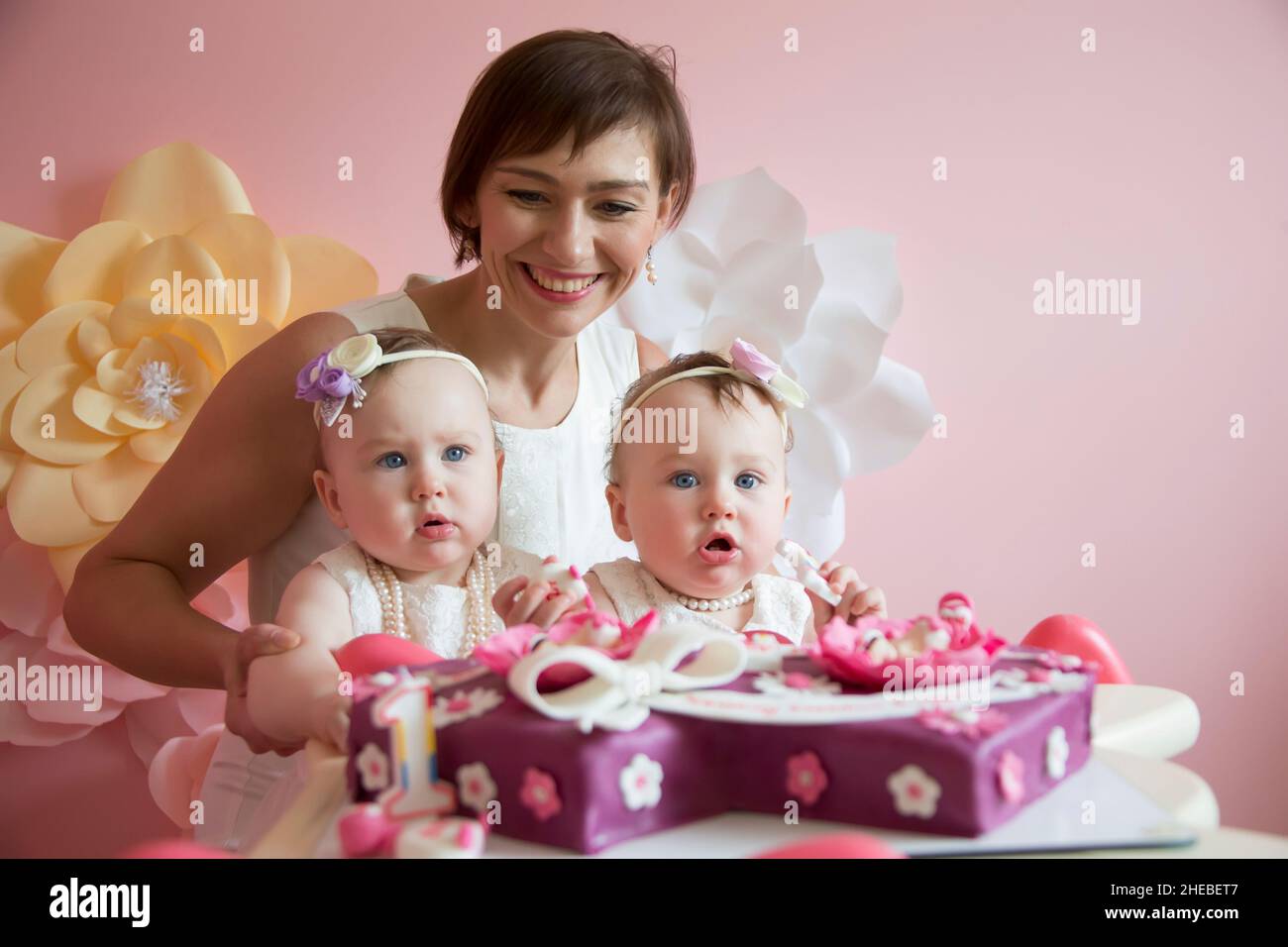 Gemelli di un anno al loro primo compleanno con la madre al compleanno ca Foto Stock