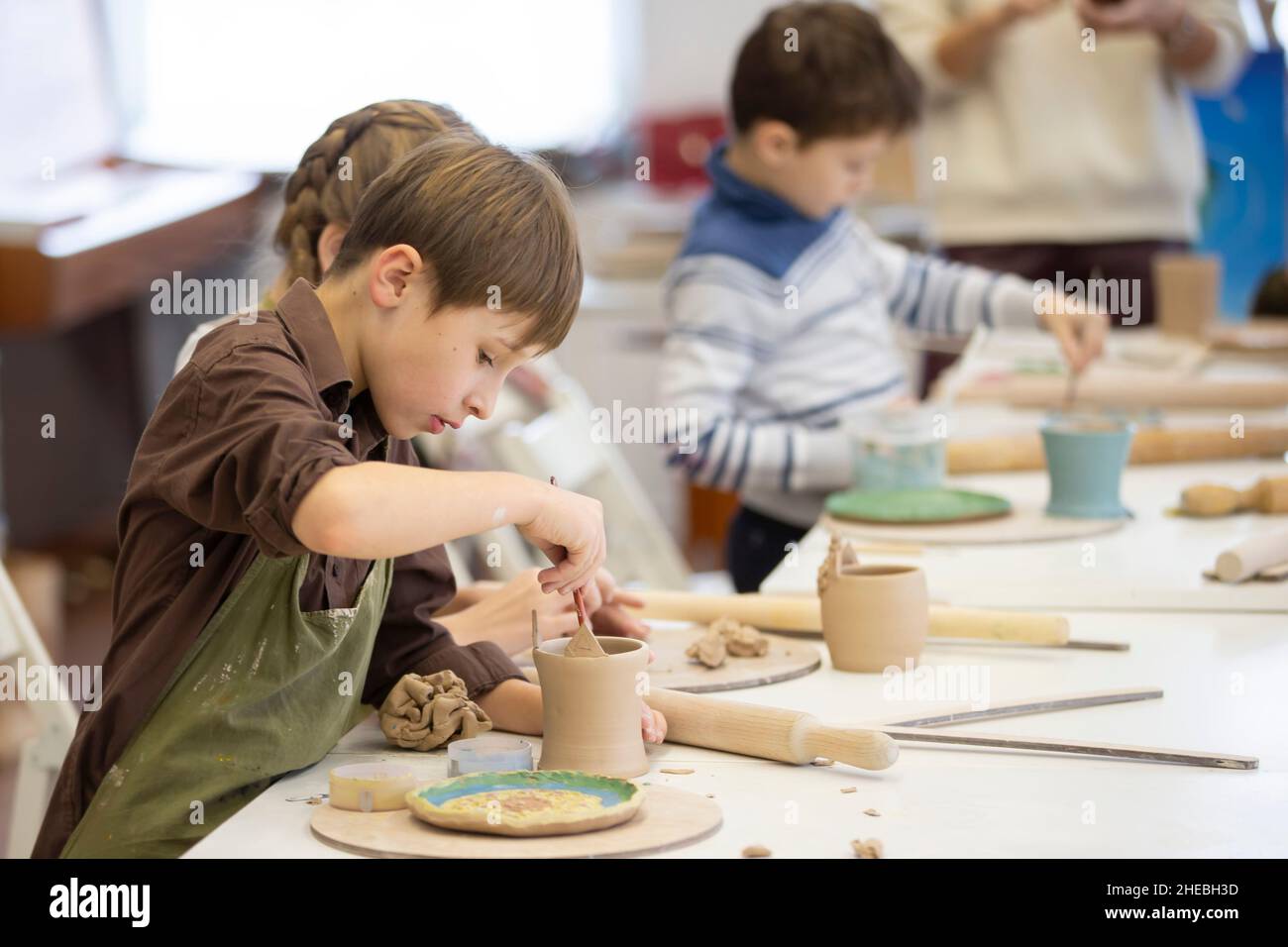 Workshop creativo. Un ragazzino fa una tazza in una lezione di modellazione dell'argilla. Foto Stock