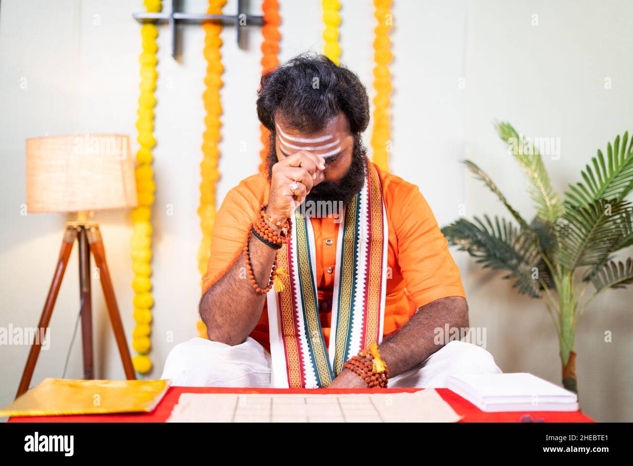 il guru santo indiano che prega dio tenendo conchiglie di cowrie cantando inni al monastero - concetto di astrologo, cultura indiana e di fortuna teller. Foto Stock