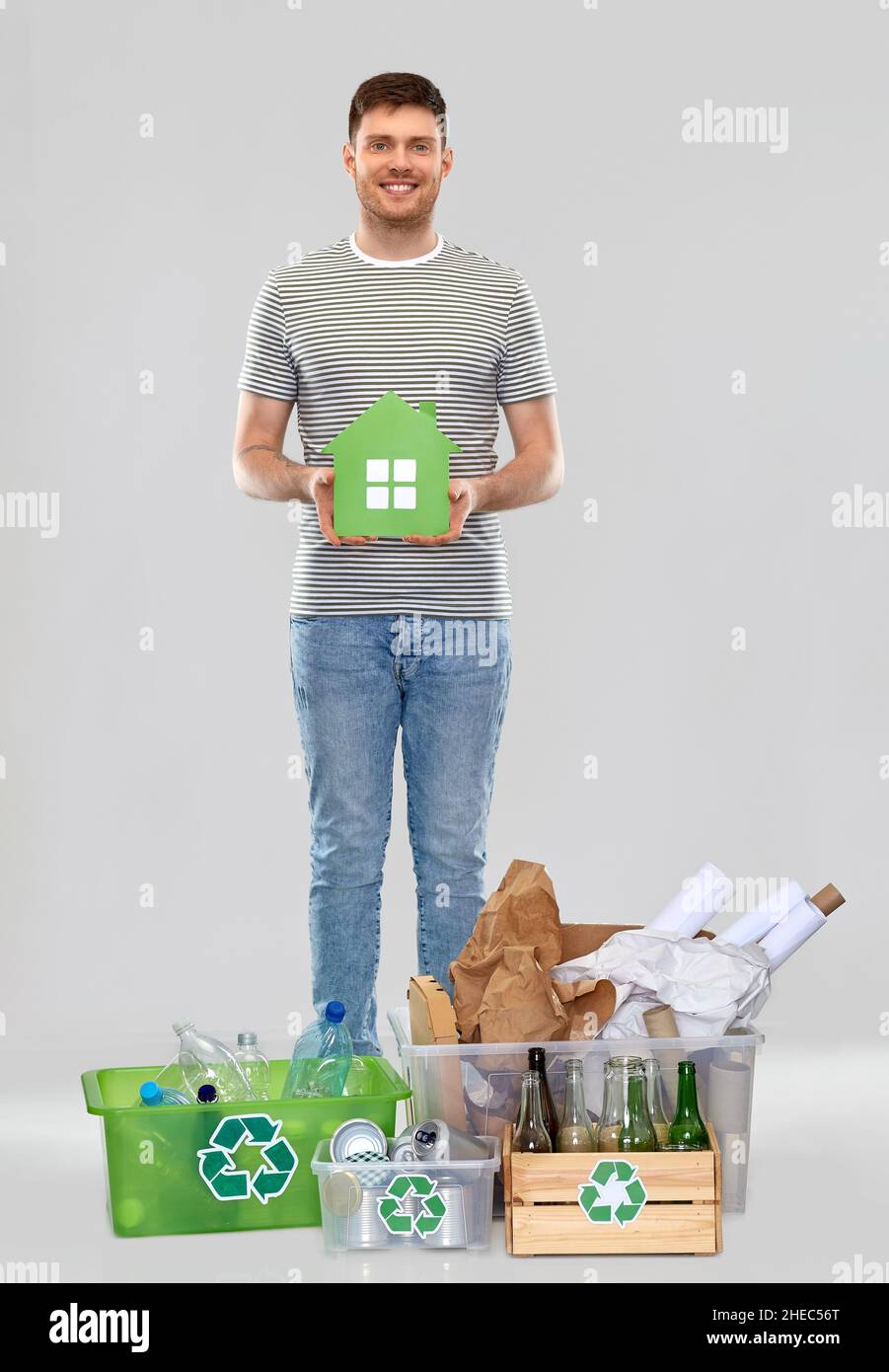 sorridente giovane uomo con casa verde smistamento rifiuti Foto Stock