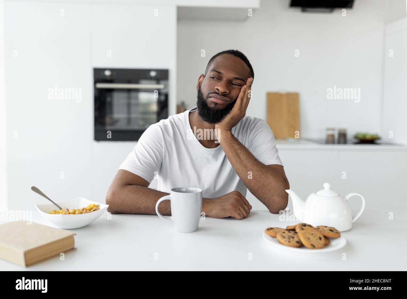 Uomo nero che soffre di insonnia seduto alla scrivania Foto Stock