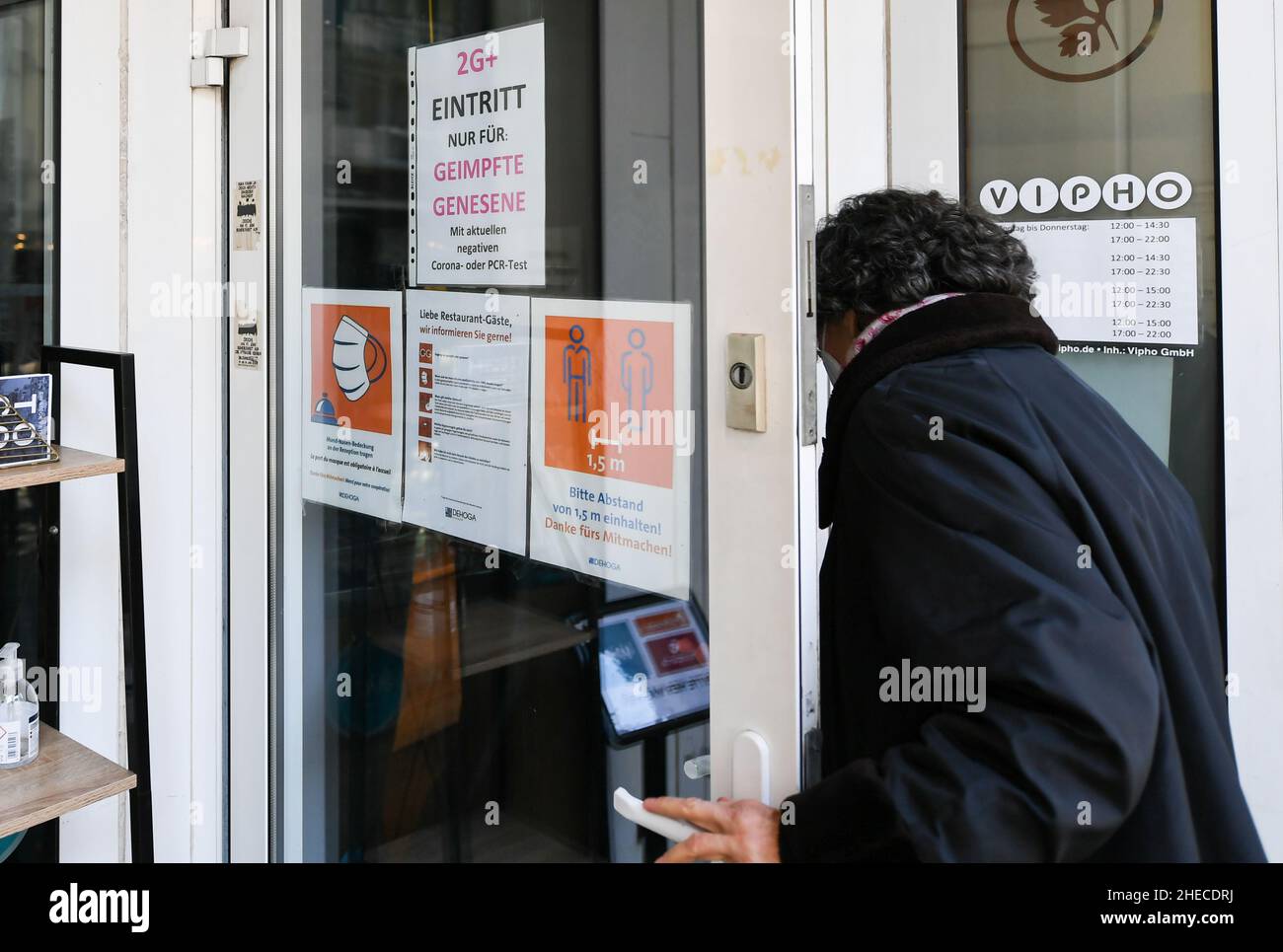 (220110) -- FRANCOFORTE, 10 gennaio 2022 (Xinhua) -- un cliente entra in un ristorante con segnali che notificano alla gente le norme antiepidemiche '2G+' contro COVID-19 a Francoforte, Germania, 10 gennaio 2022. Il tasso di incidenza di sette giorni COVID-19 della Germania per 100.000 abitanti ha continuato ad aumentare e ha raggiunto 375,7, in aumento da 362,7 il giorno precedente, il Robert Koch Institute (RKI) per le malattie infettive riferite il lunedì. Venerdì scorso, i governi statali tedeschi e federali avevano concordato una cosiddetta regola del 2G-Plus per il settore gastronomico, limitando l'accesso alle persone vaccinate e ricoverate con C negativa Foto Stock