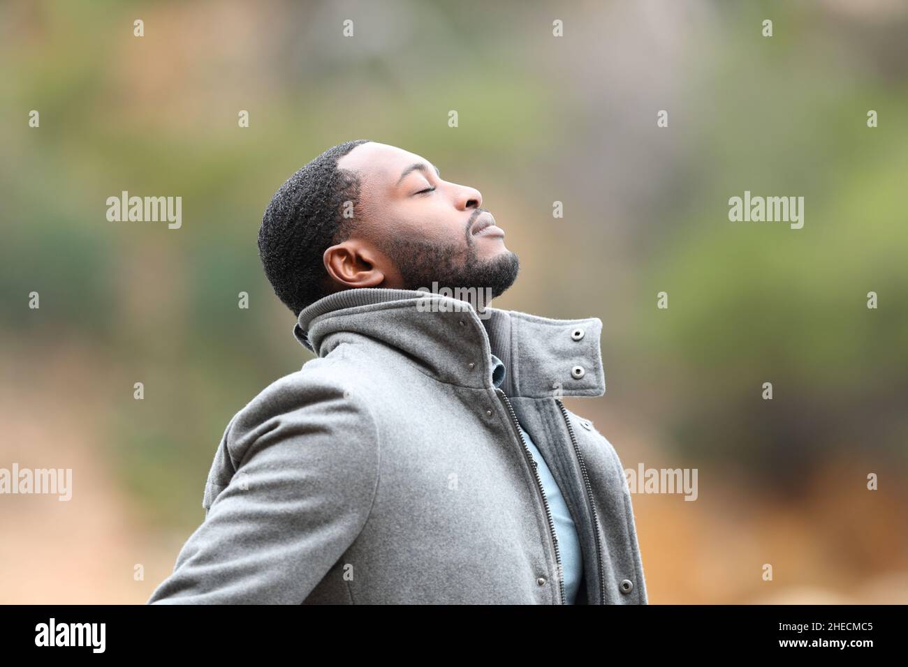 Uomo rilassato con pelle nera in inverno respirando aria fresca all'aperto Foto Stock