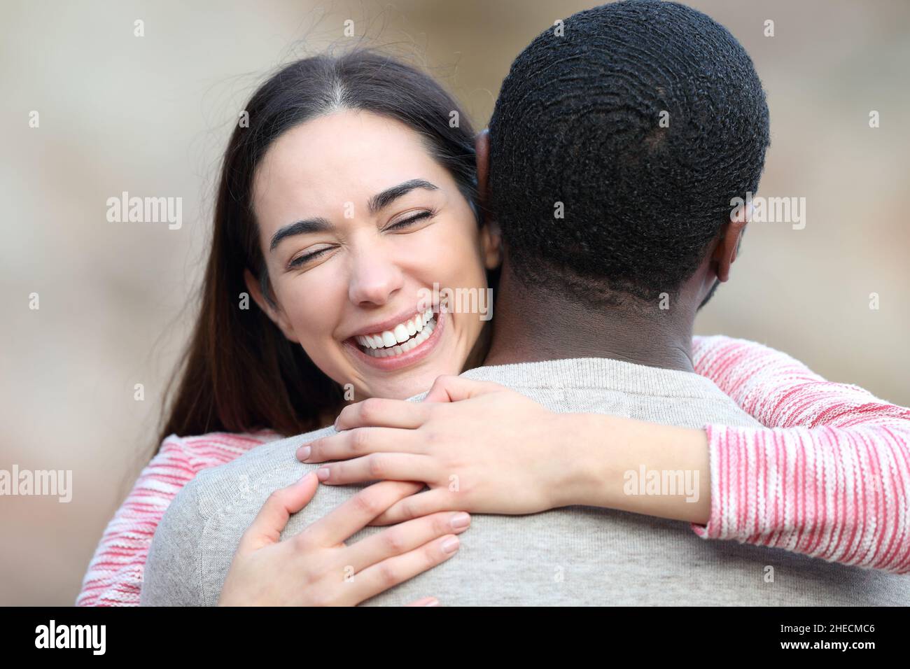 Felice donna caucasica che abbraccia la sua amica con la pelle nera Foto Stock