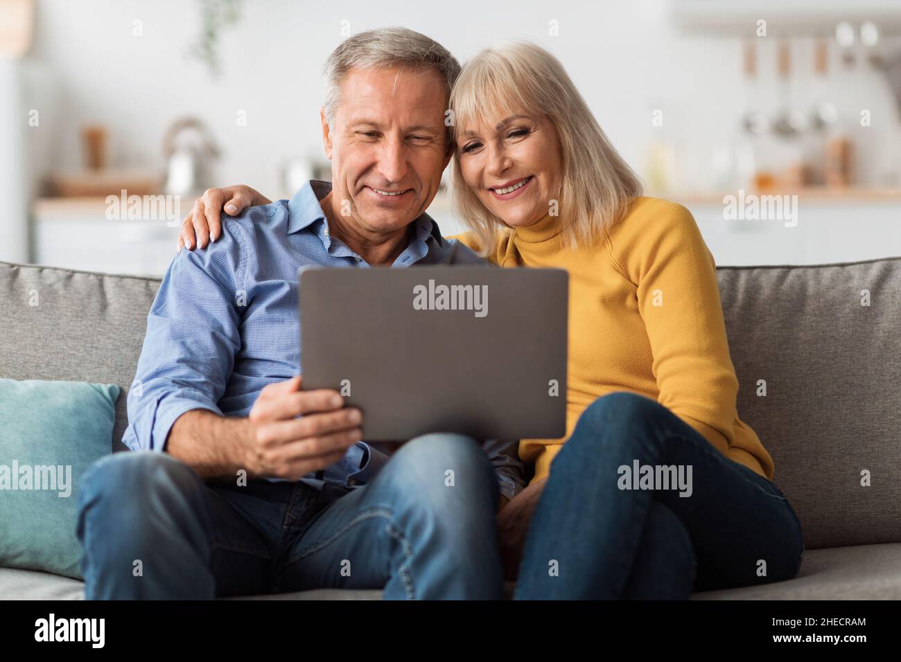 Marito e moglie senior che utilizzano un computer portatile che si integra a casa Foto Stock