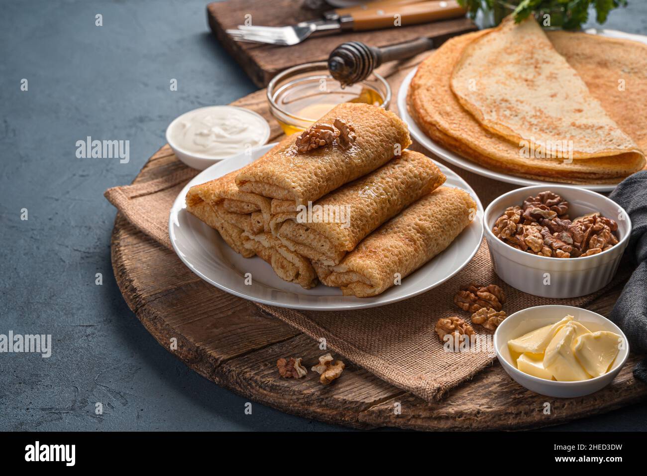 Pancake farciti su sfondo con noci, miele e panna acida. Mardi Gras. Vista laterale, spazio di copia. Foto Stock