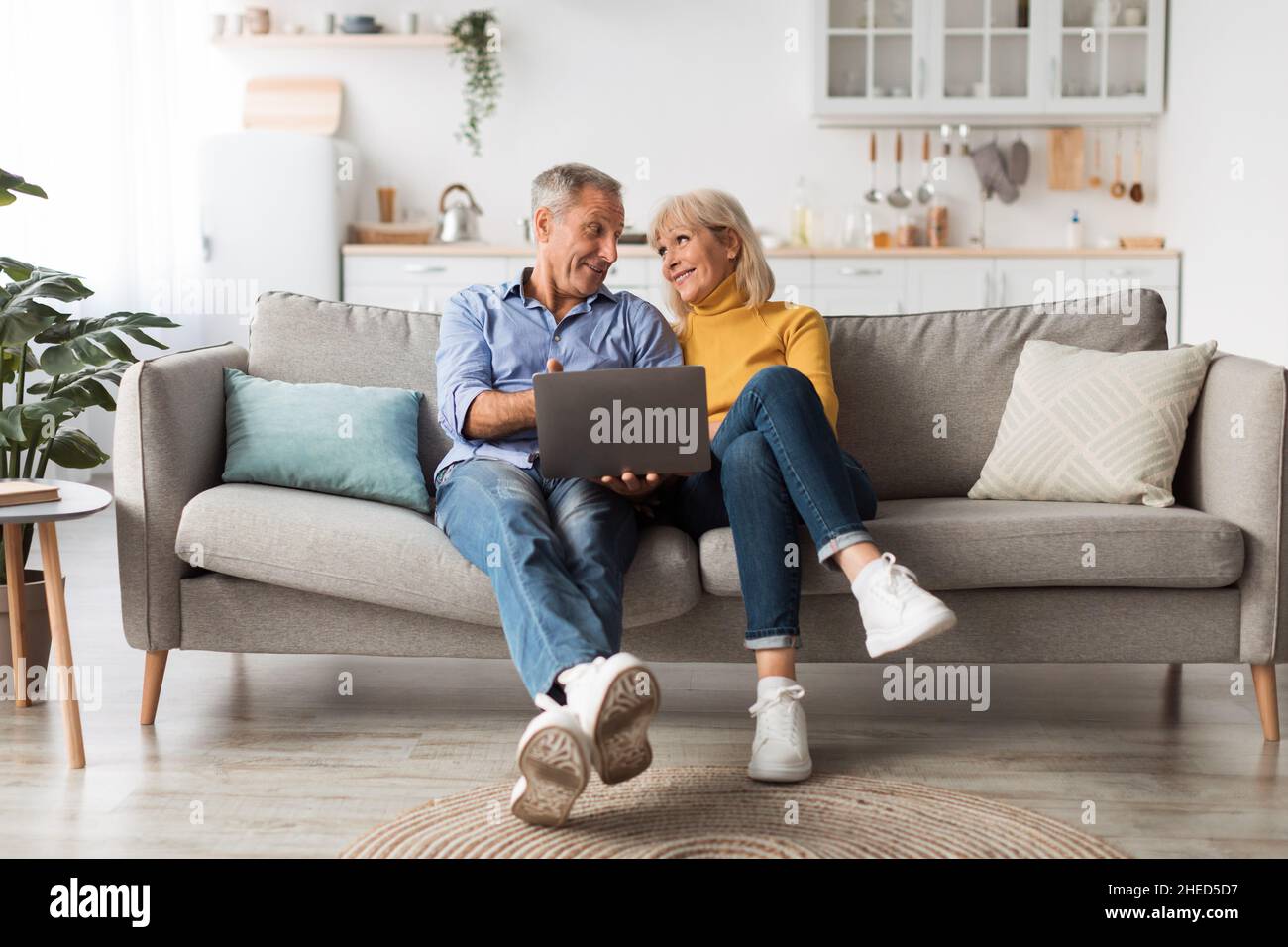 Coppia anziana che utilizza un computer portatile seduto sul divano di casa Foto Stock