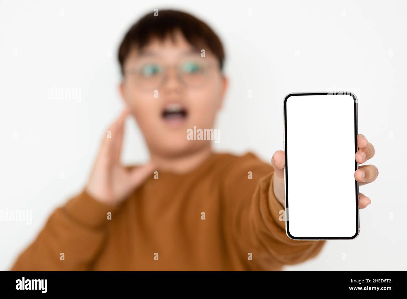 Ragazzo emozionale asiatico che mostra smartphone con schermo vuoto, mockup Foto Stock