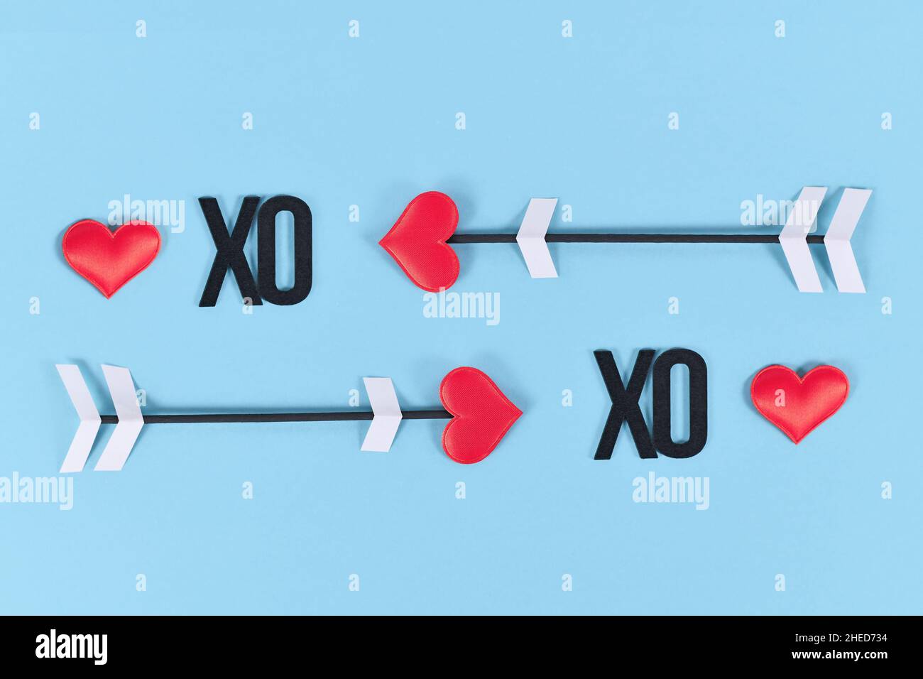 San Valentino amore freccia sabbia XO lettere di testo su sfondo blu Foto Stock