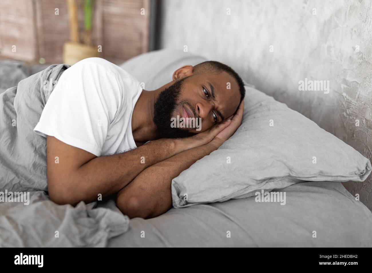 Uomo nero che si trova a letto e pensando Foto Stock