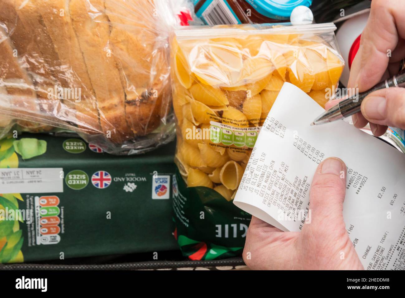 Donna che controlla i suoi generi alimentari contro un supermercato fino al rotolo - budgeting per ridurre il suo costo di vita. Foto Stock