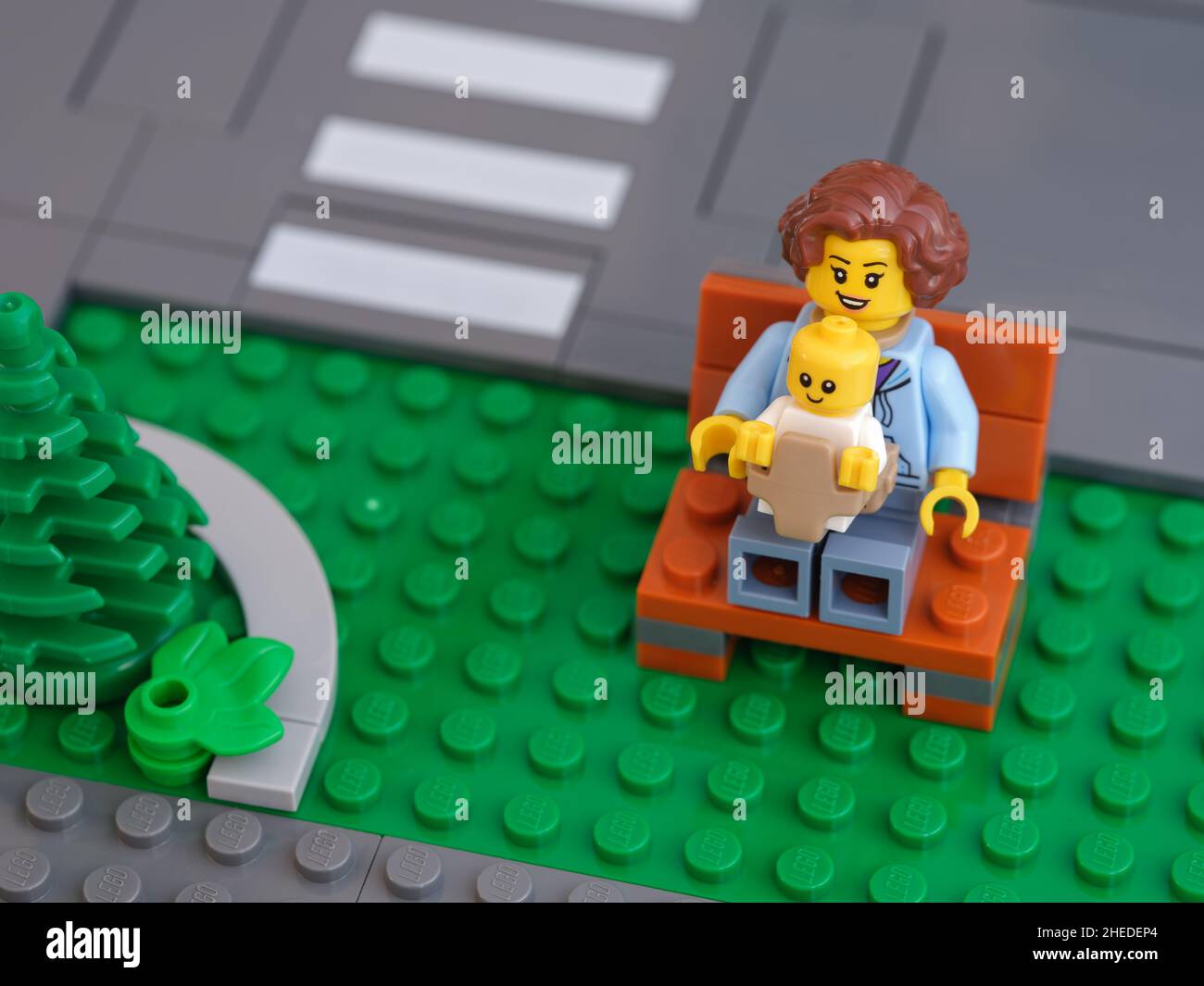 Tambov, Federazione Russa - 08 gennaio 2022 una minifcifra della madre di Lego con un bambino in un portatore del bambino seduto su una panchina in un parco della città. Foto Stock