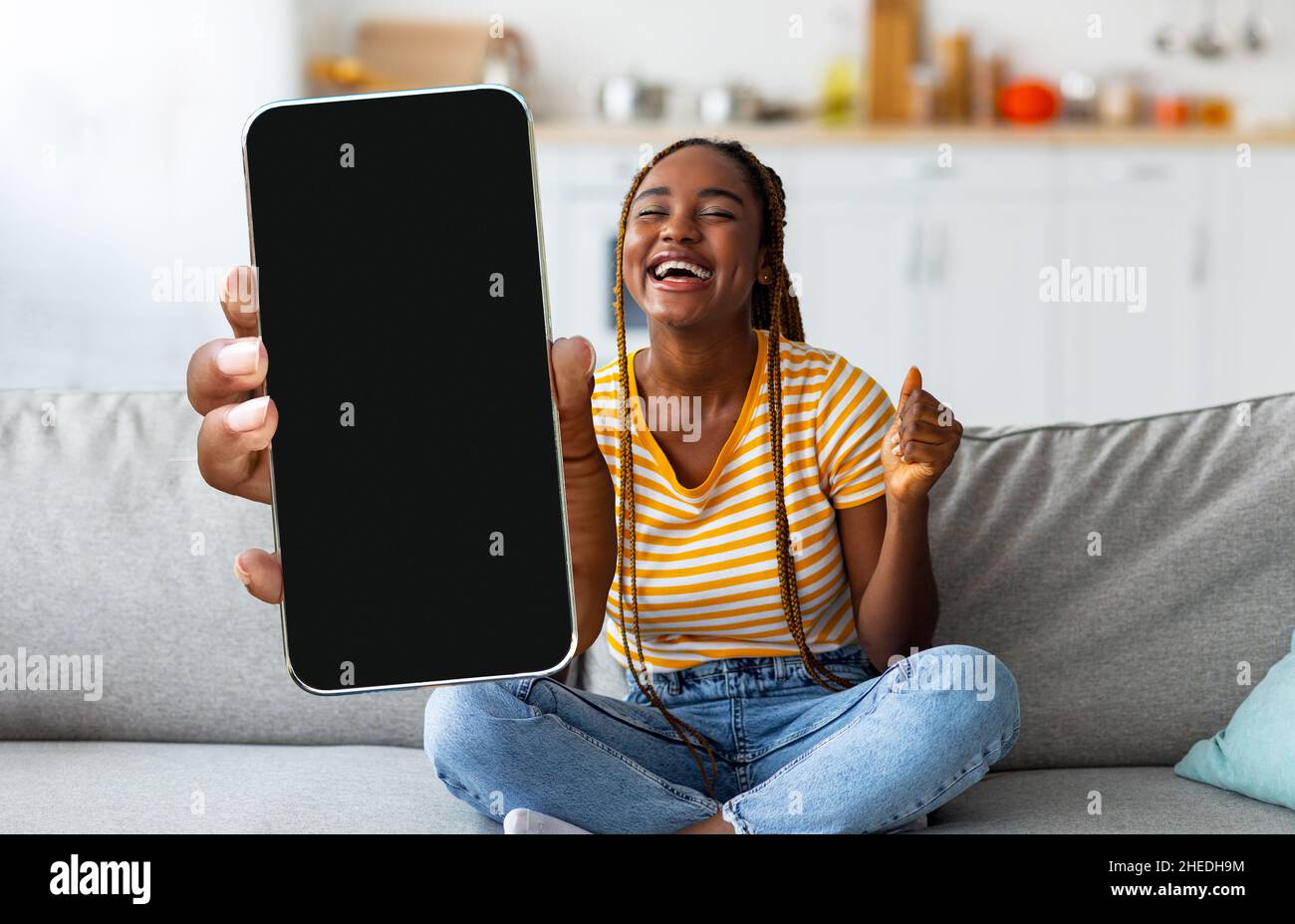 Smartphone Excited Black Young Woman Holding con grande schermo vuoto a casa Foto Stock