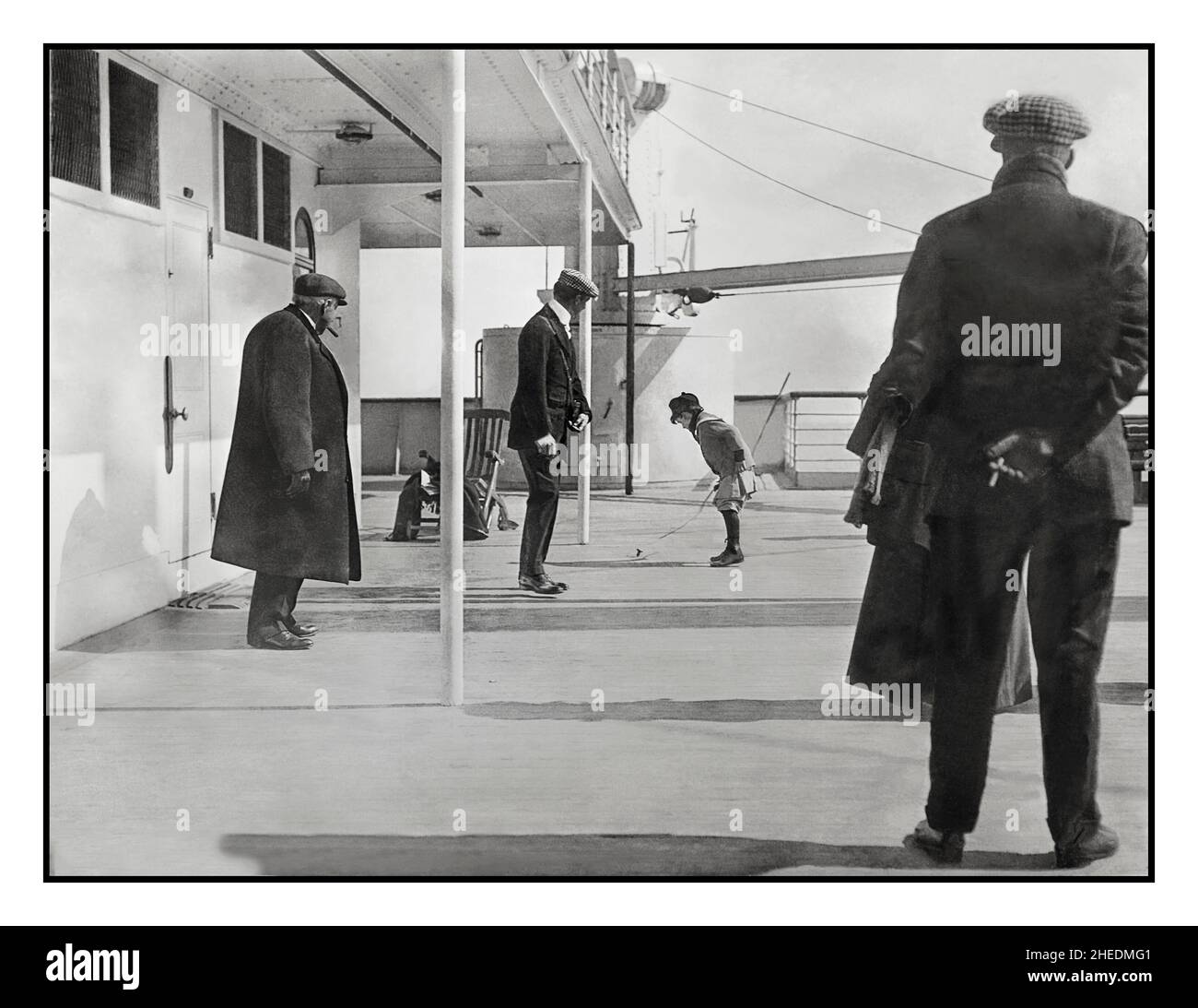 Passeggeri di RMS Titanic sulla passeggiata a poppa Dell'A-Deck: Robert Douglas Speden, sei anni fa, gettando un top rotante, sotto l'occhio vigile di suo padre, Frederick. 11th aprile 1912 3 giorni prima che il Titanic affondasse tragicamente dopo aver colpito un iceberg, questa foto scattata all'inizio del primo viaggio del Titanic, il passeggero Douglas Spedden può essere visto giocare con la sua parte superiore sul ponte di passeggiata della nave. Per tutti i sei anni Douglas Spedden si sarebbe ricordato, è andato a dormire tranquillamente nella sua cabina di prima classe sulla RMS Titanic, e poi si è svegliato all'alba in una scialuppa di salvataggio lunga nove metri. Foto Stock