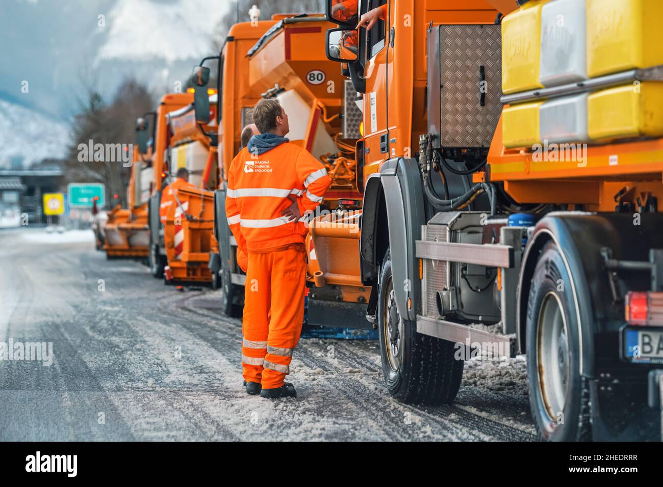 Liptovsky Hradok, Slovacchia - 12 febbraio 2020: Gruppo di carrelli di manutenzione stradale arancione brillante con sale di sghiacciamento pronto per l'inverno, neve cov Foto Stock