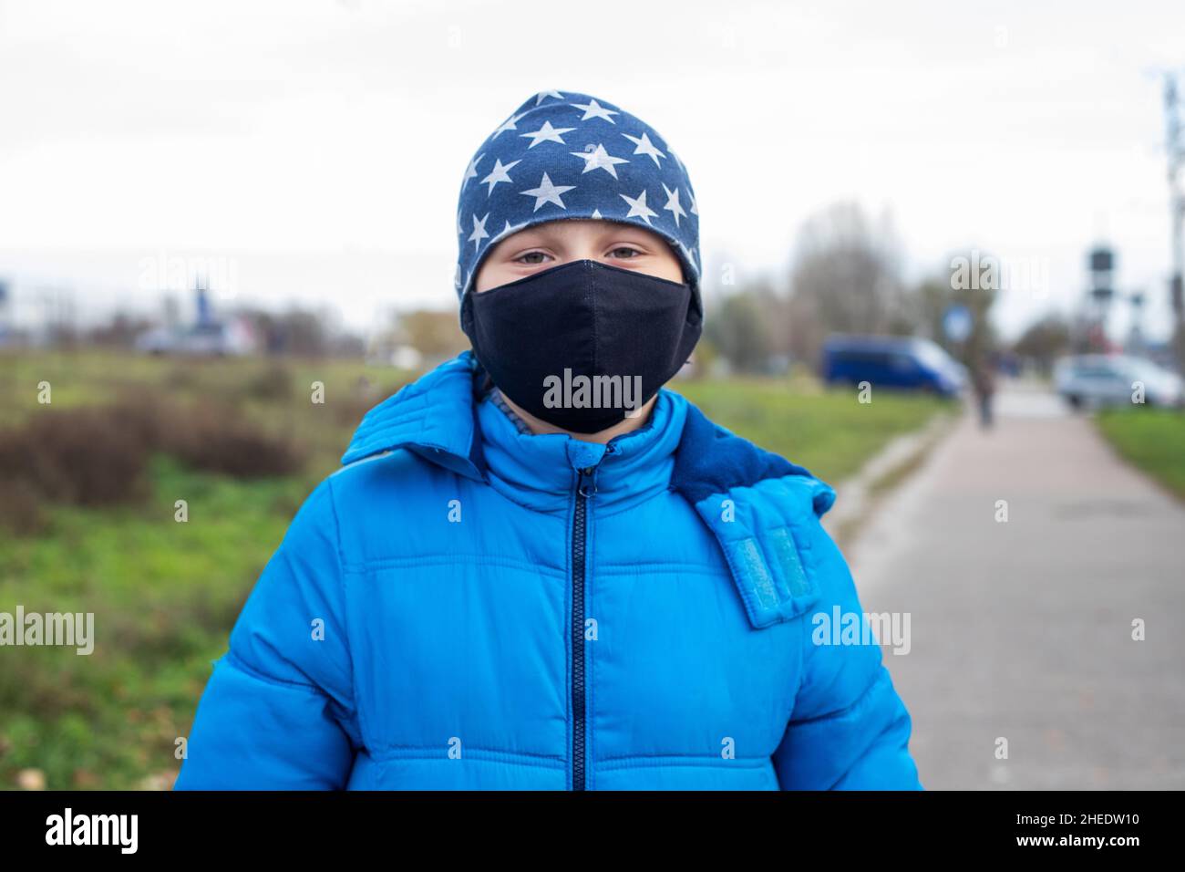 Ritratto di ragazzo di 10 anni in giacca blu calda indossando maschera nera fatta in casa durante la quarantena. Coronavirus, Covid-19 e concetto pandemico Foto Stock