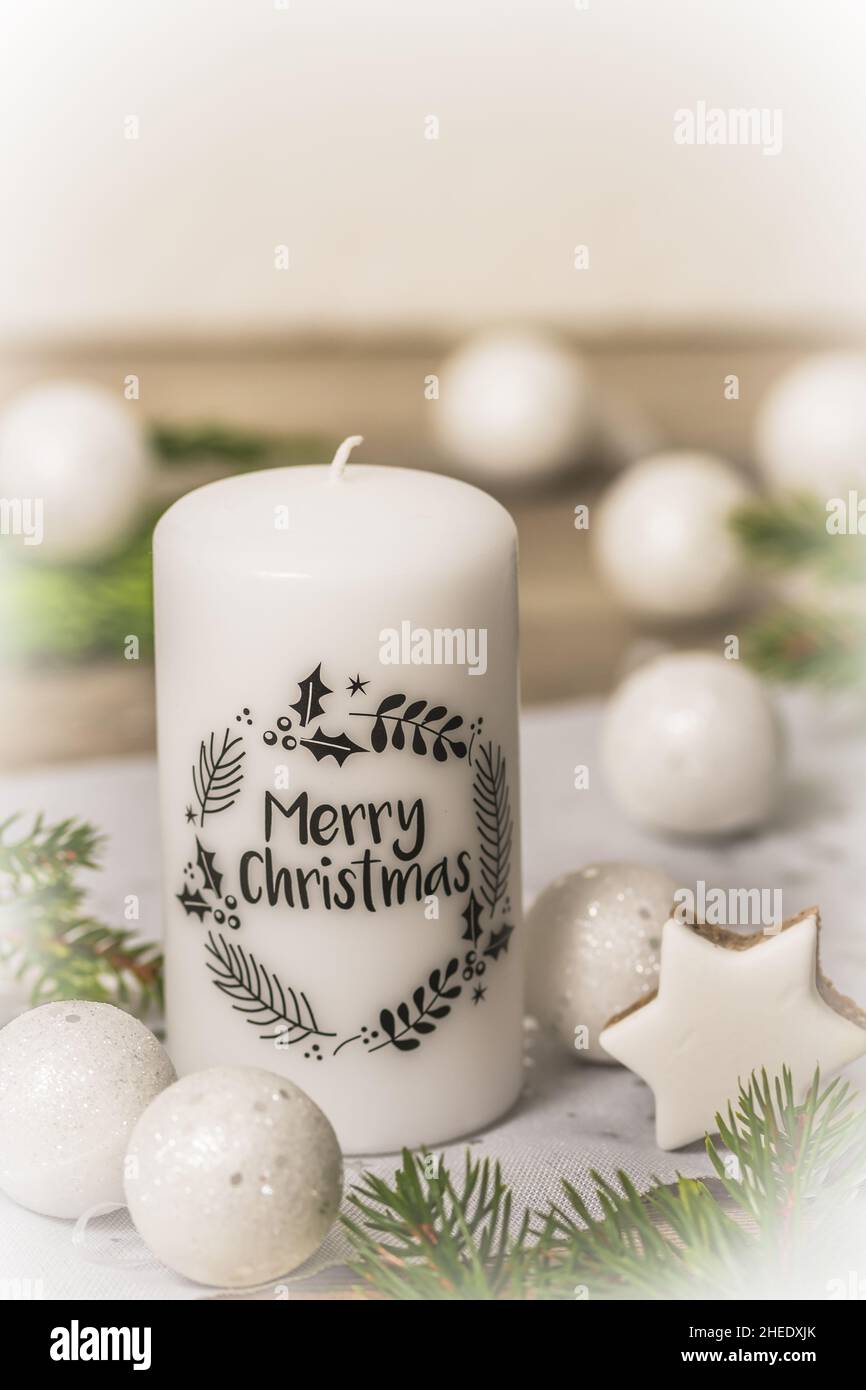 Candela bianca con testo nero buon Natale e decorazione di natale su tavola di legno, verticale Foto Stock