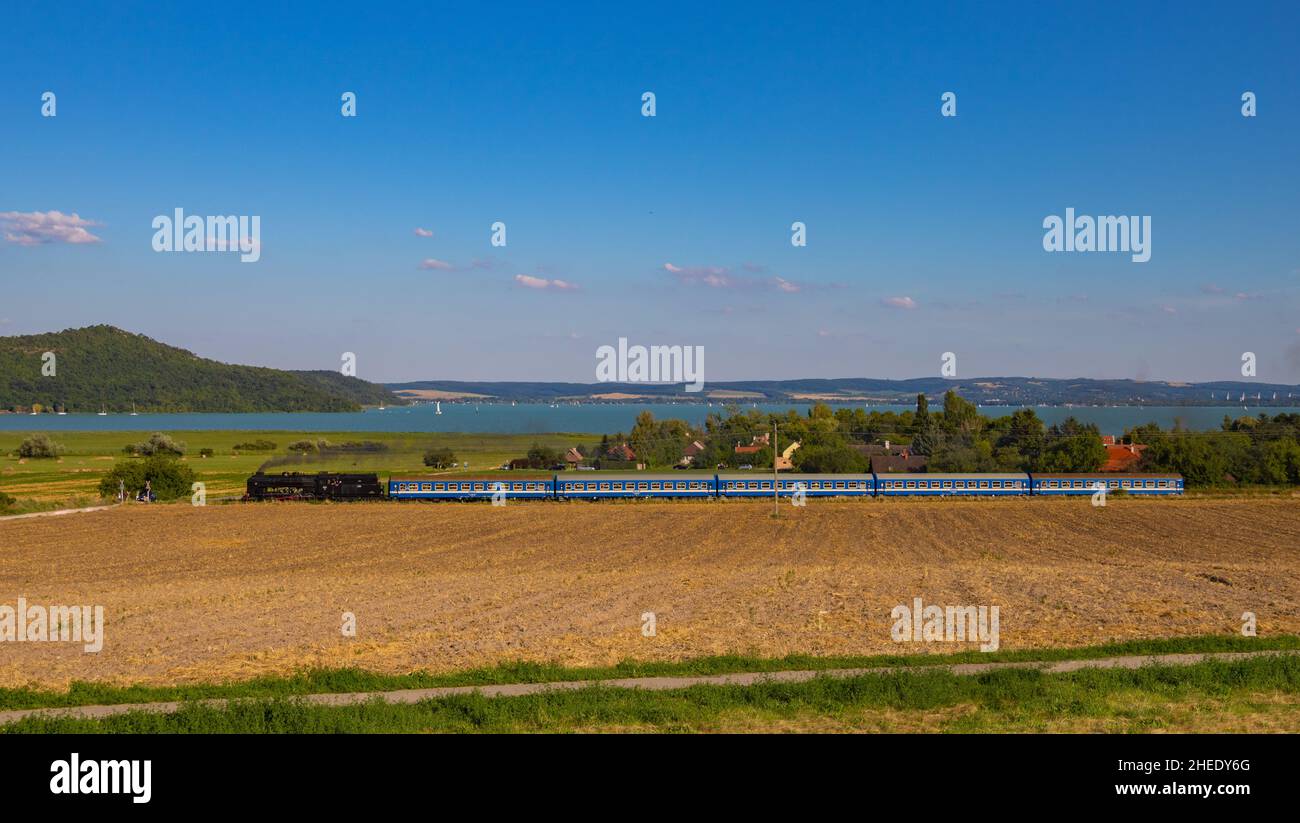 Il motore a vapore ungherese MÁV 424 con un treno nostalgico sulla strada per Balatonfüred da Tapolca e Balaton e Tihany è sullo sfondo. Foto Stock