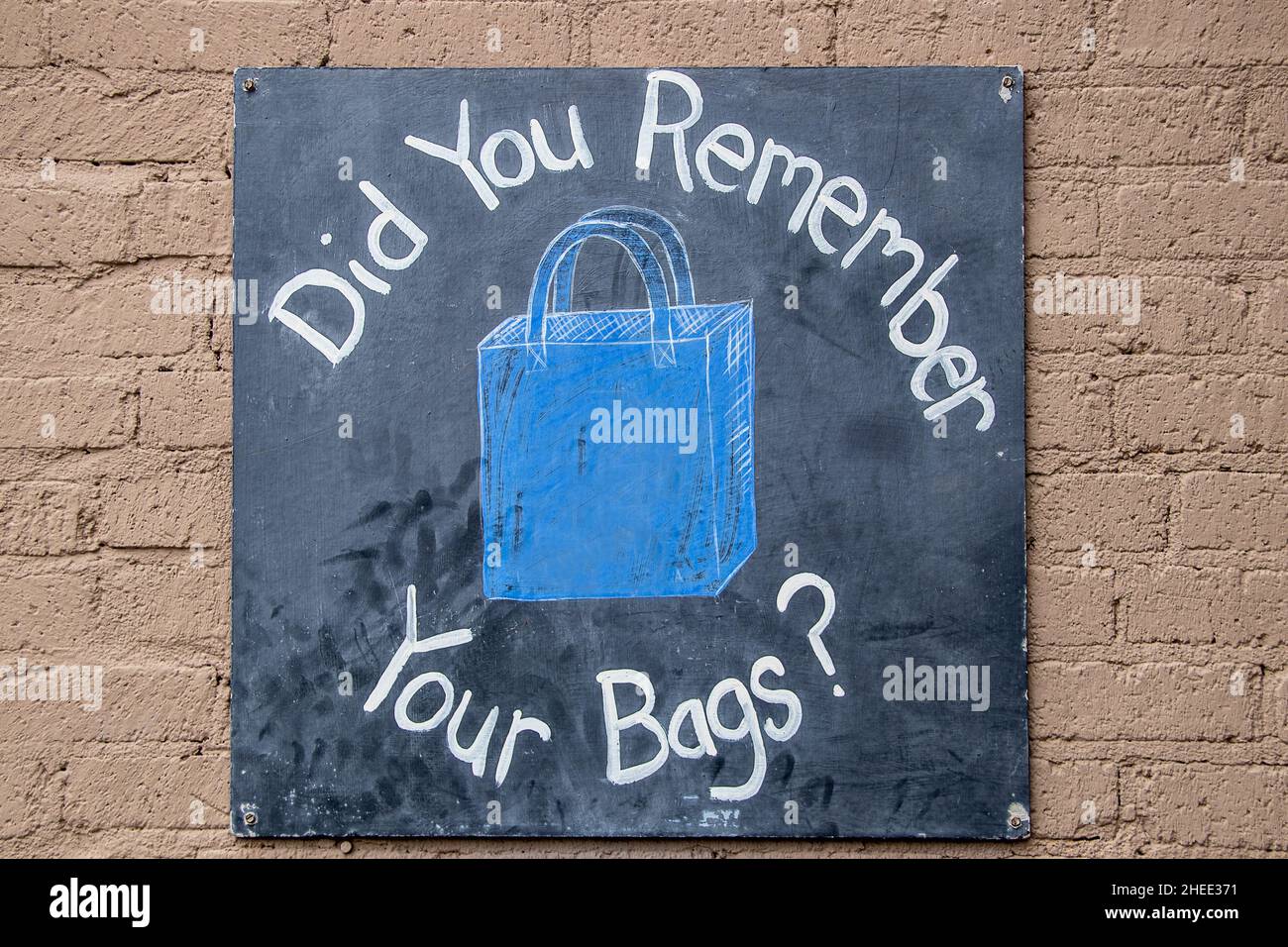 Ti ricordi le tue borse- cartello nero verniciato avvitato su muro di cemento verniciato. Foto Stock