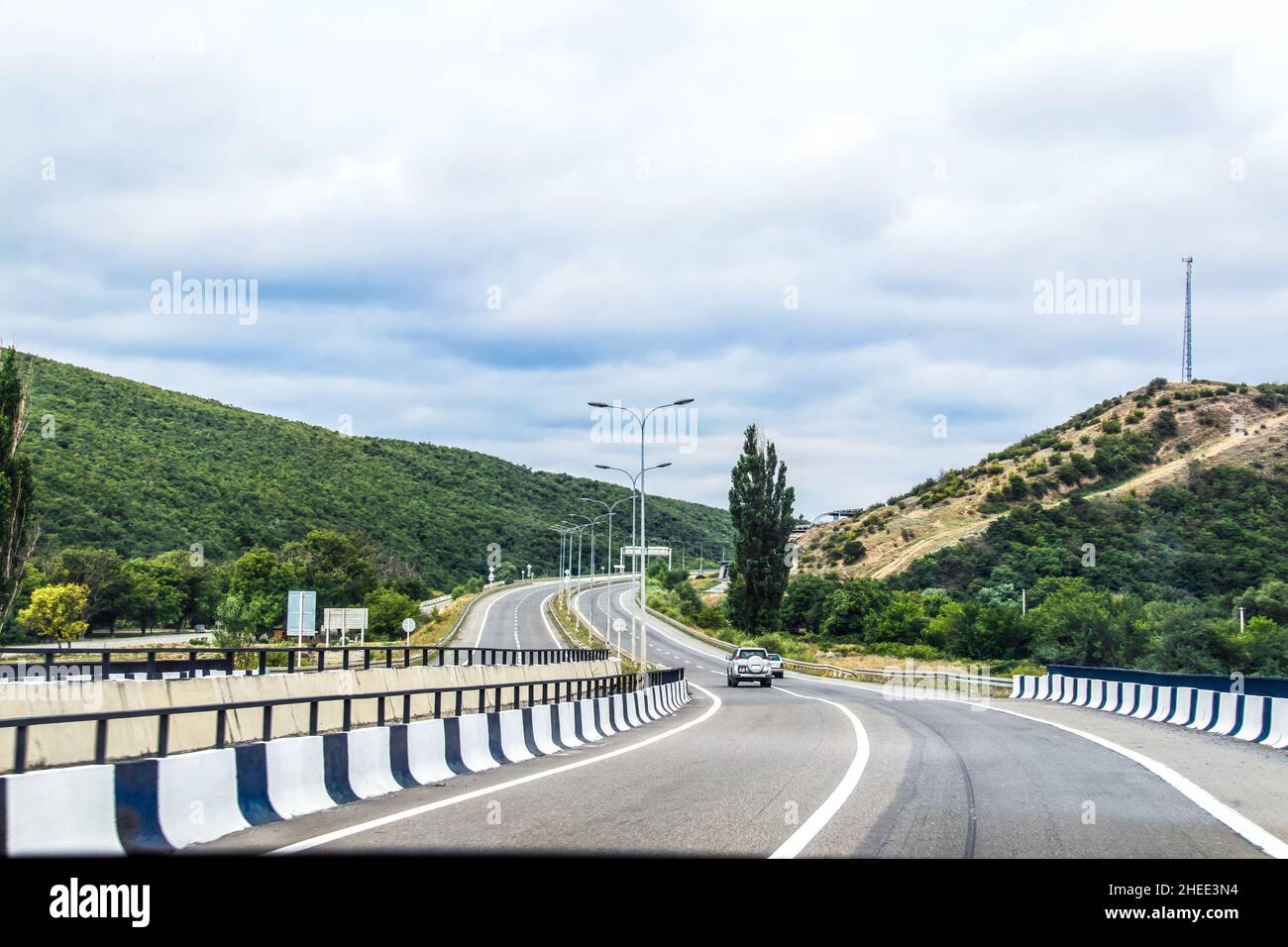 Guida a nord fuori da Tbilisi Georgia in una giornata estiva con auto e SUV andando intorno curva avanti Foto Stock
