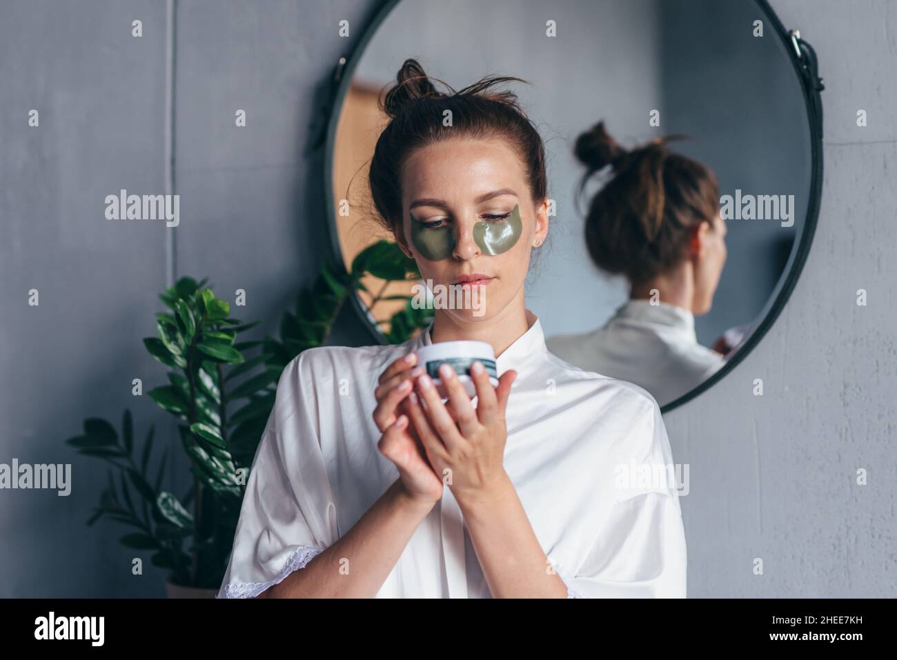 Donna che tiene un vaso di cerotti occhi mentre si trova in bagno. Foto Stock