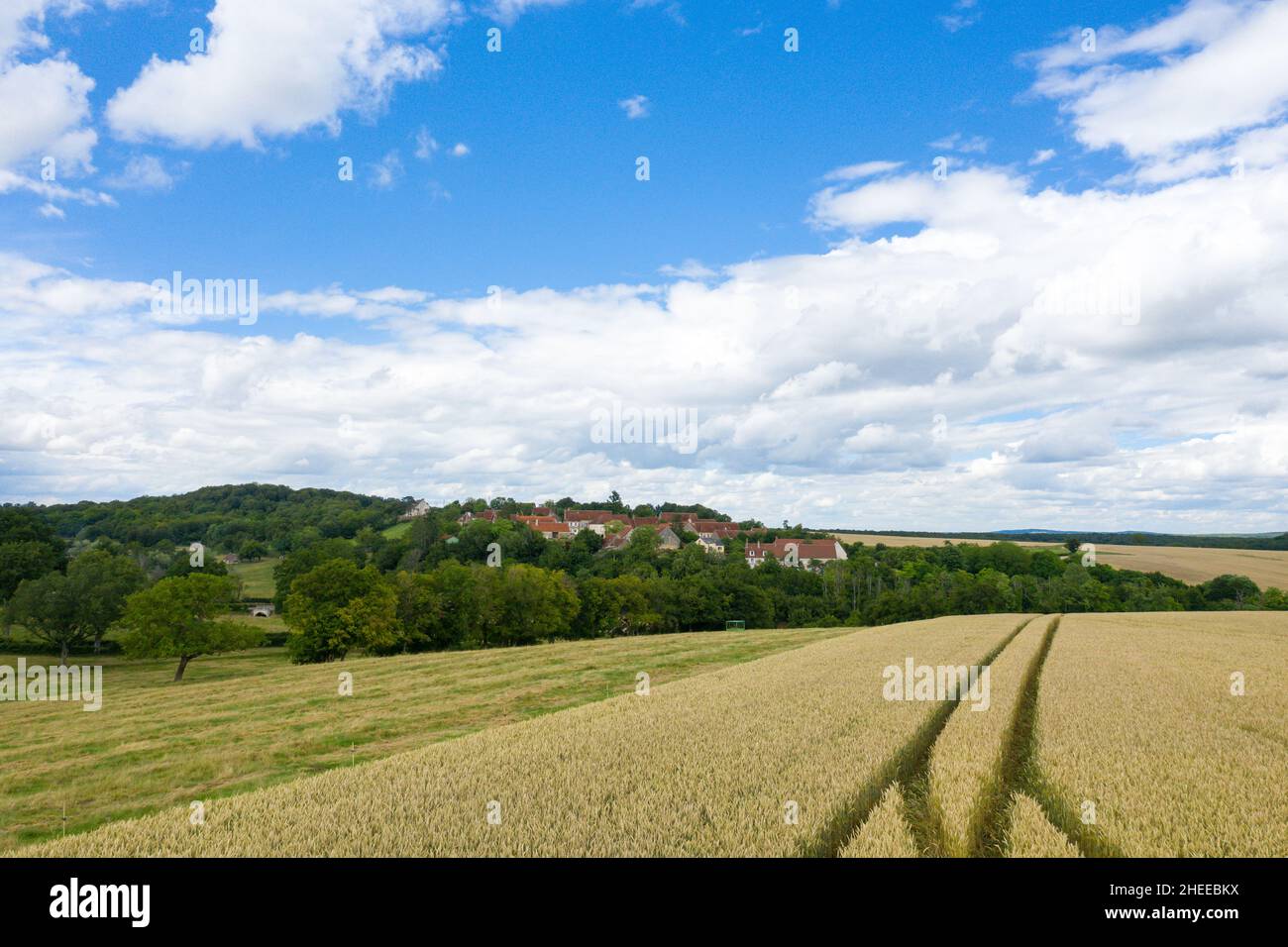 Questa foto di paesaggio è stata scattata in Europa, Francia, Borgogna, Nievre, in estate. Vediamo le ruote di un trattore al centro di un campo di grano davanti Foto Stock