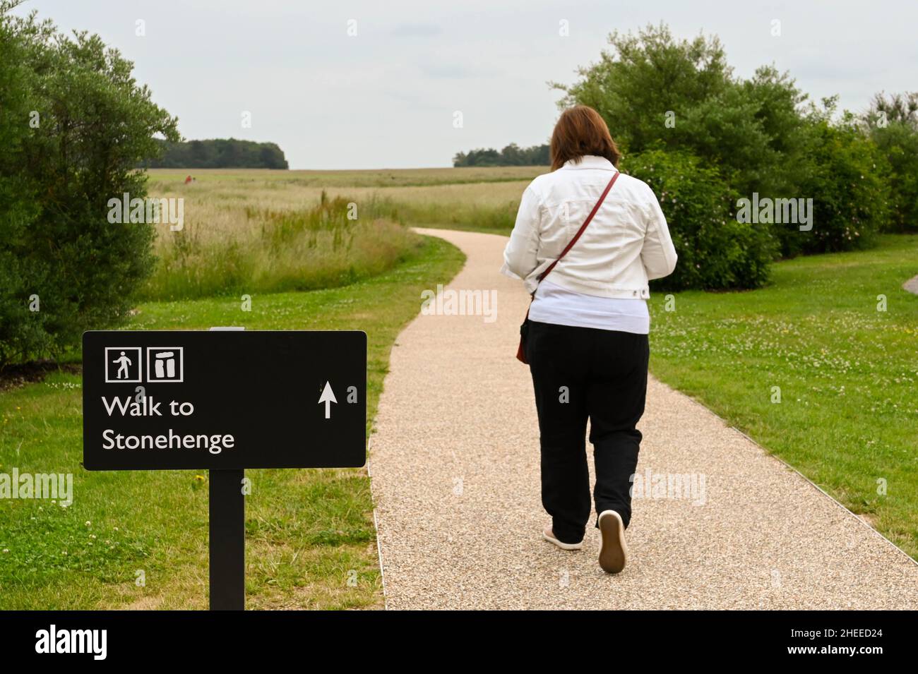 Stonehenge, Inghilterra - Giugno 20231: Persona che cammina oltre un cartello direzionale su un sentiero per raggiungere il monumento a Stonehenge. Foto Stock