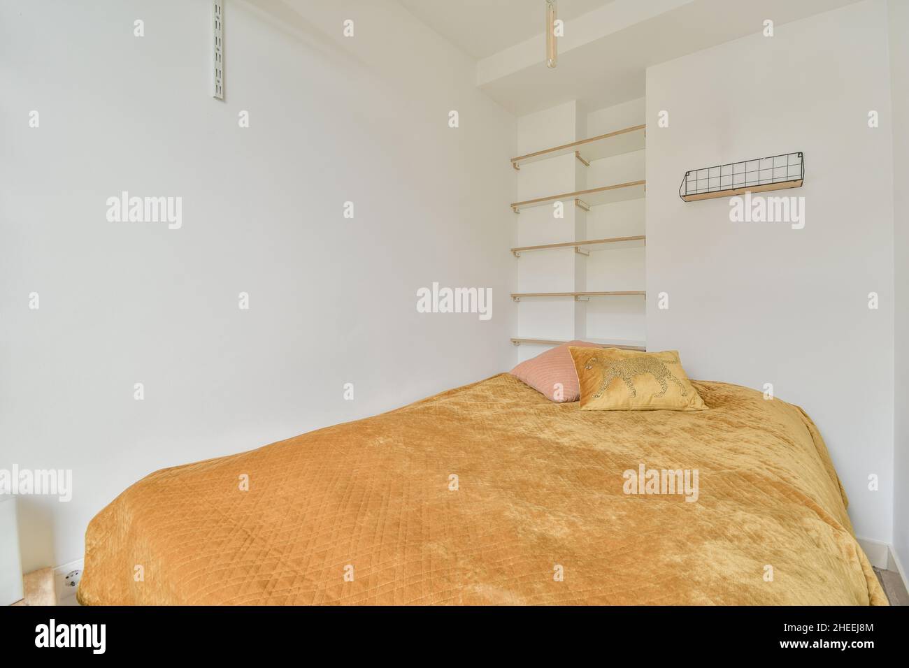 Interno della camera da letto con pareti bianche e letto morbido con cuscini e coperta gialla Foto Stock