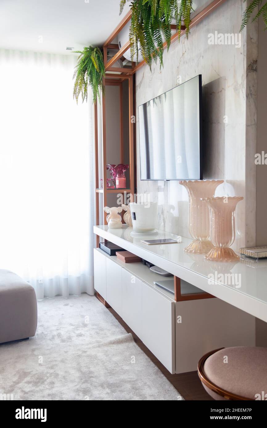 Interno del soggiorno con TV set appeso su parete di marmo sopra ripiano lucido con vasi di vetro Foto Stock