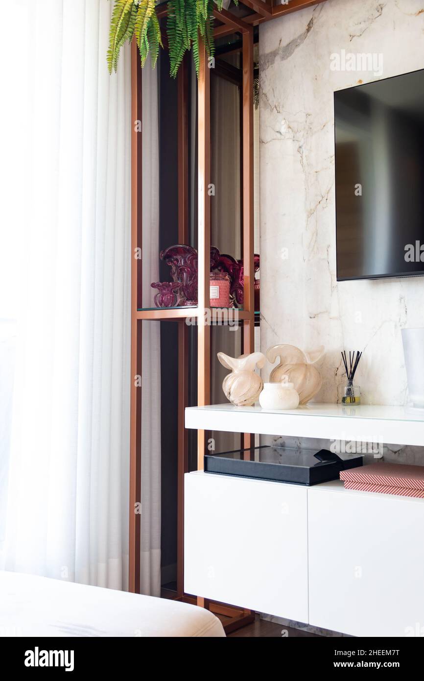 Interno del soggiorno con TV set appeso su parete di marmo sopra ripiano lucido con vasi di vetro Foto Stock