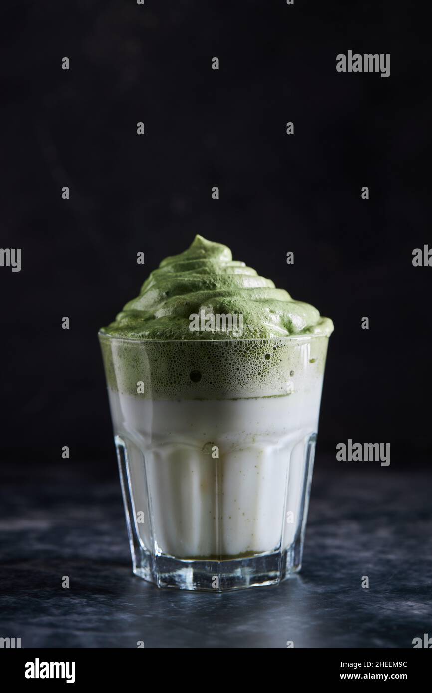 Bicchiere di caffè dalgona fresco con matcha posto sulla superficie grigia Foto Stock