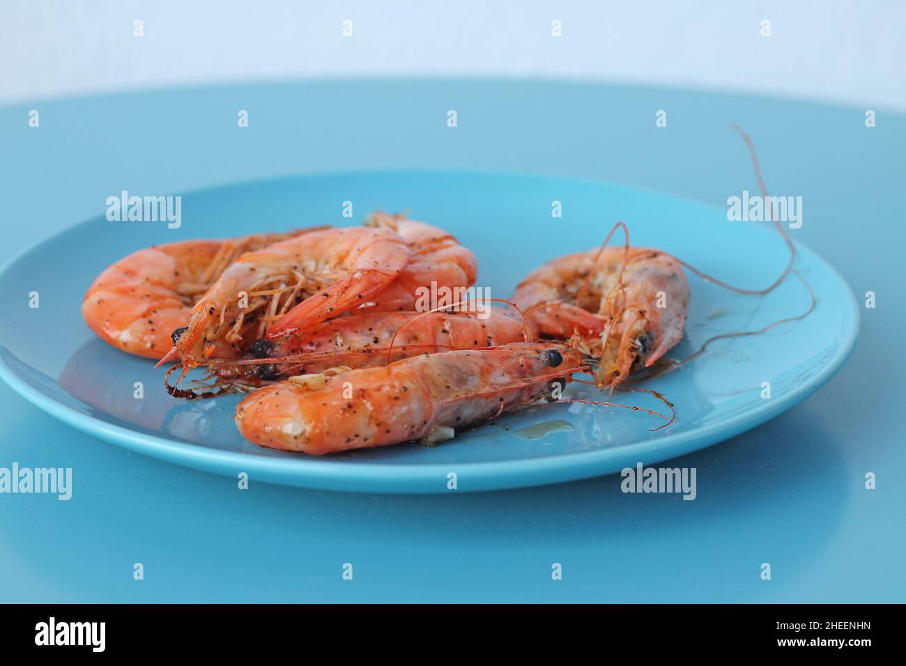 Gamberetti bolliti su piatto blu. Cibo di mare sano. Foto Stock