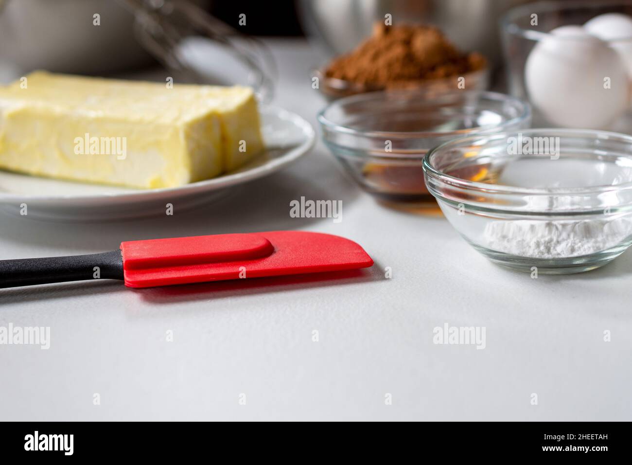 Vista laterale degli ingredienti di cottura. Gli ingredienti includono: Uova, burro, vaniglia, cacao e lievito in polvere. Foto Stock