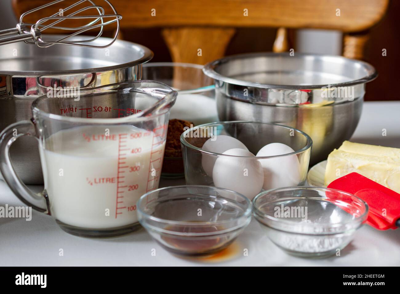 Ingredienti disposti prima della cottura. Gli ingredienti includono: Uova, latte, cacao, burro e lievito in polvere. Foto Stock