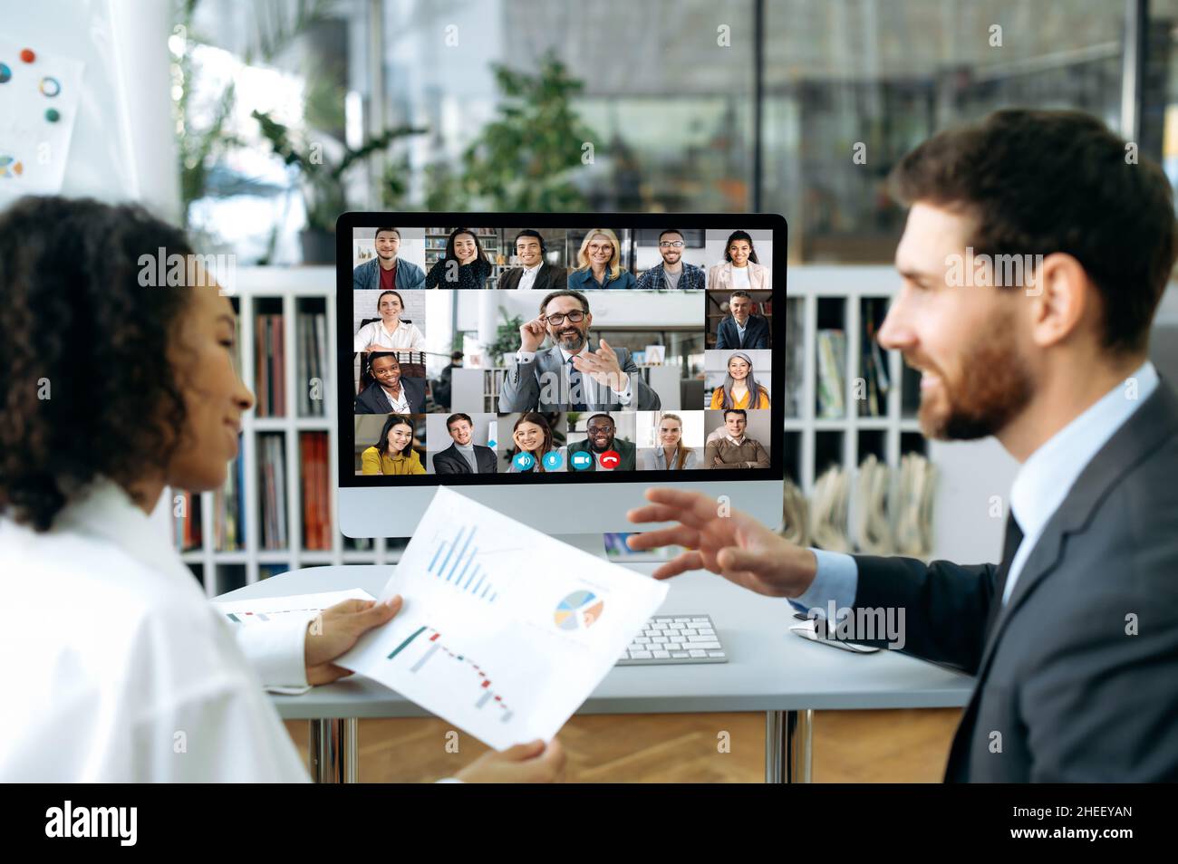 Un gruppo di partner commerciali si è riunito in una videoconferenza online per discutere i piani finanziari dell'azienda. Uomo d'affari e donna di diverse nazionalità che parlano in videochiamata con i colleghi Foto Stock