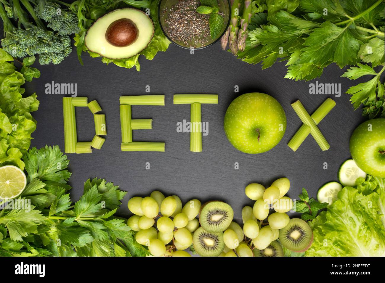 Vista dall'alto di verdure fresche e frutta verdi con parola detox su sfondo nero. Disintossicare la dieta, mangiare sano e pulito Foto Stock
