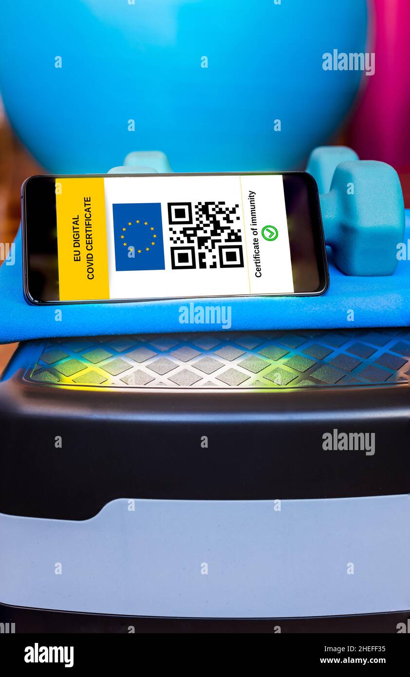 Schermo mobile con certificato digitale europeo di vaccinazione con codice QR sulle attrezzature sportive in palestra. Foto Stock