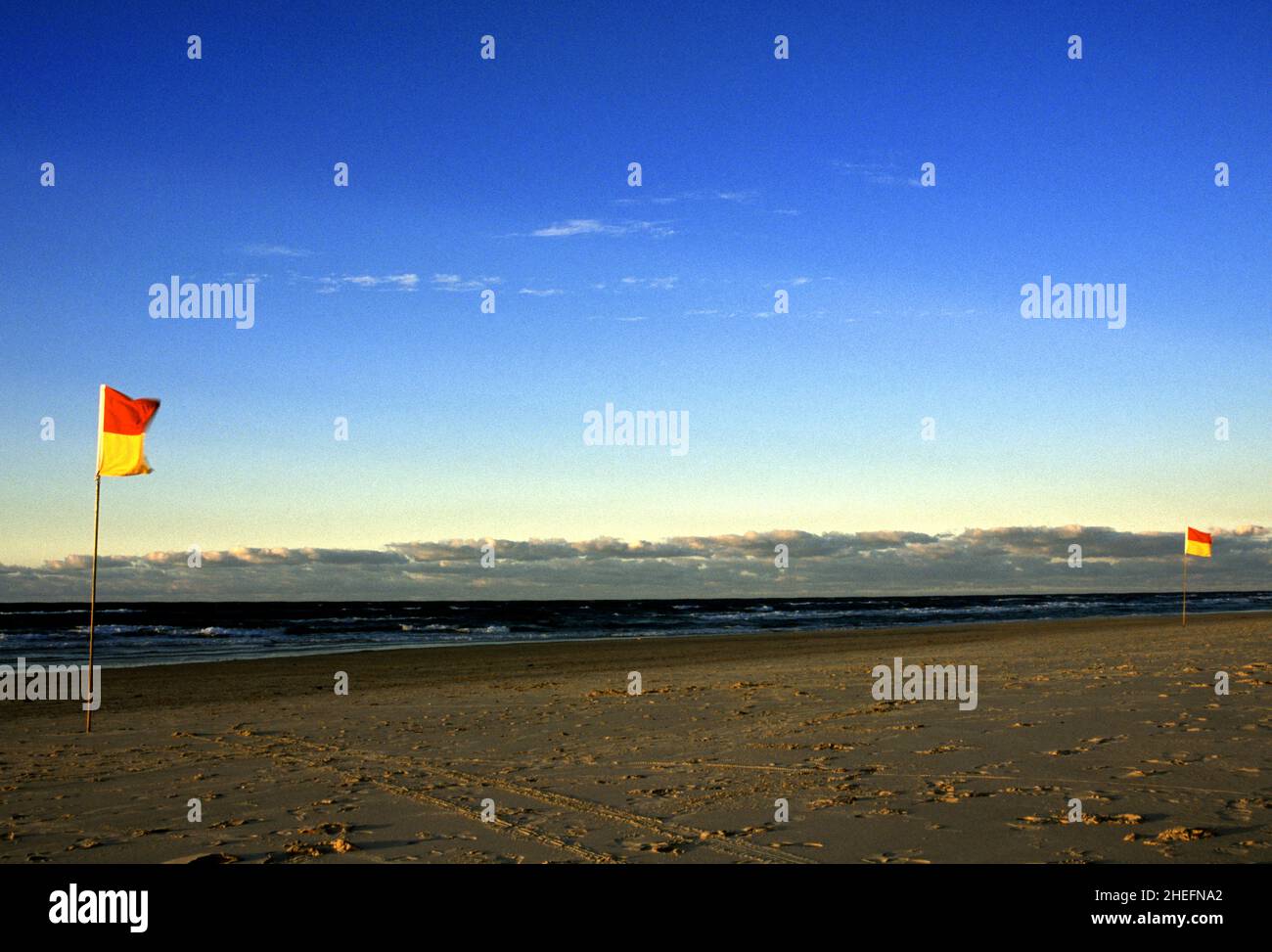 Fotografia a colori delle bandiere della spiaggia, della costa oceanica e delle onde che si infrangono al tramonto, Kirra Beach, Gold Coast, Queensland, Australia, 2005. Foto Stock